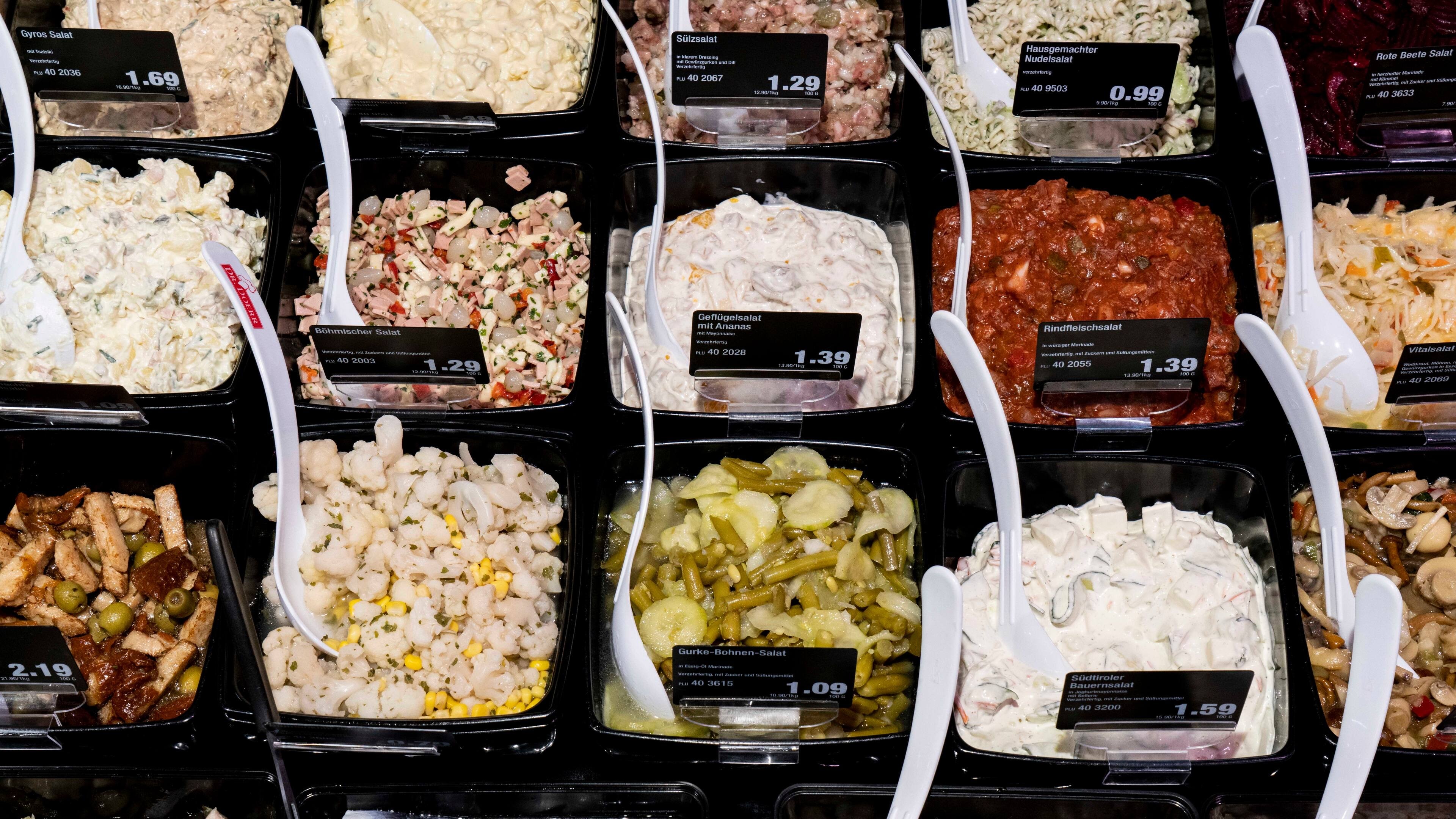 Verschiedene Schüsseln mit Salaten in der Auslage einer Bedientheke.