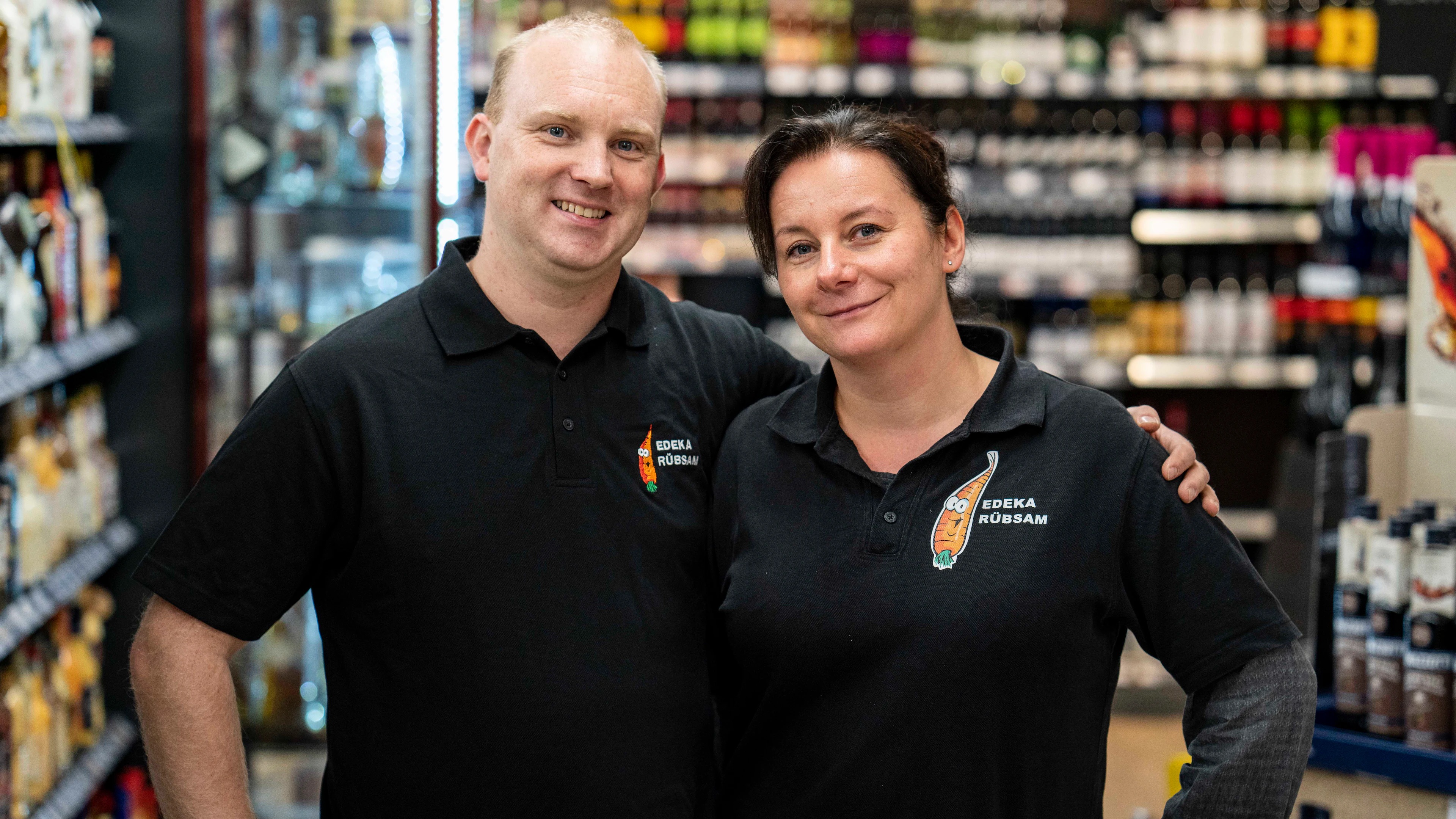 Zwei lächelnde Mitarbeitende eines EDEKA-Marktes.
