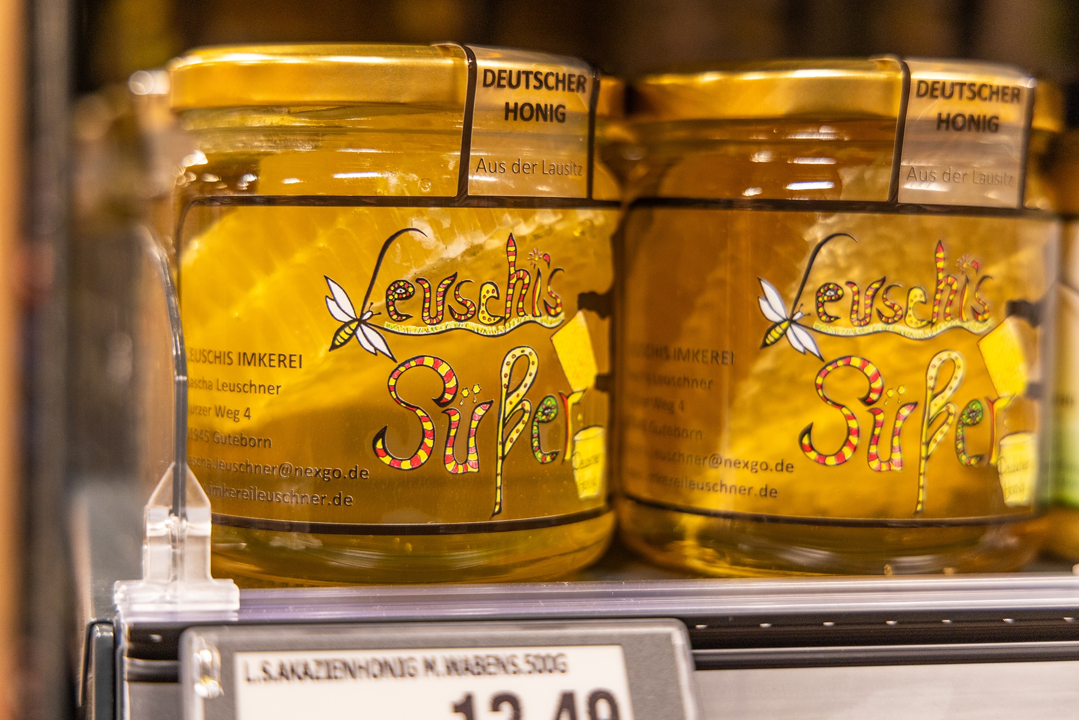Zwie Honiggläser von Leuschis Imkerei im Regal.