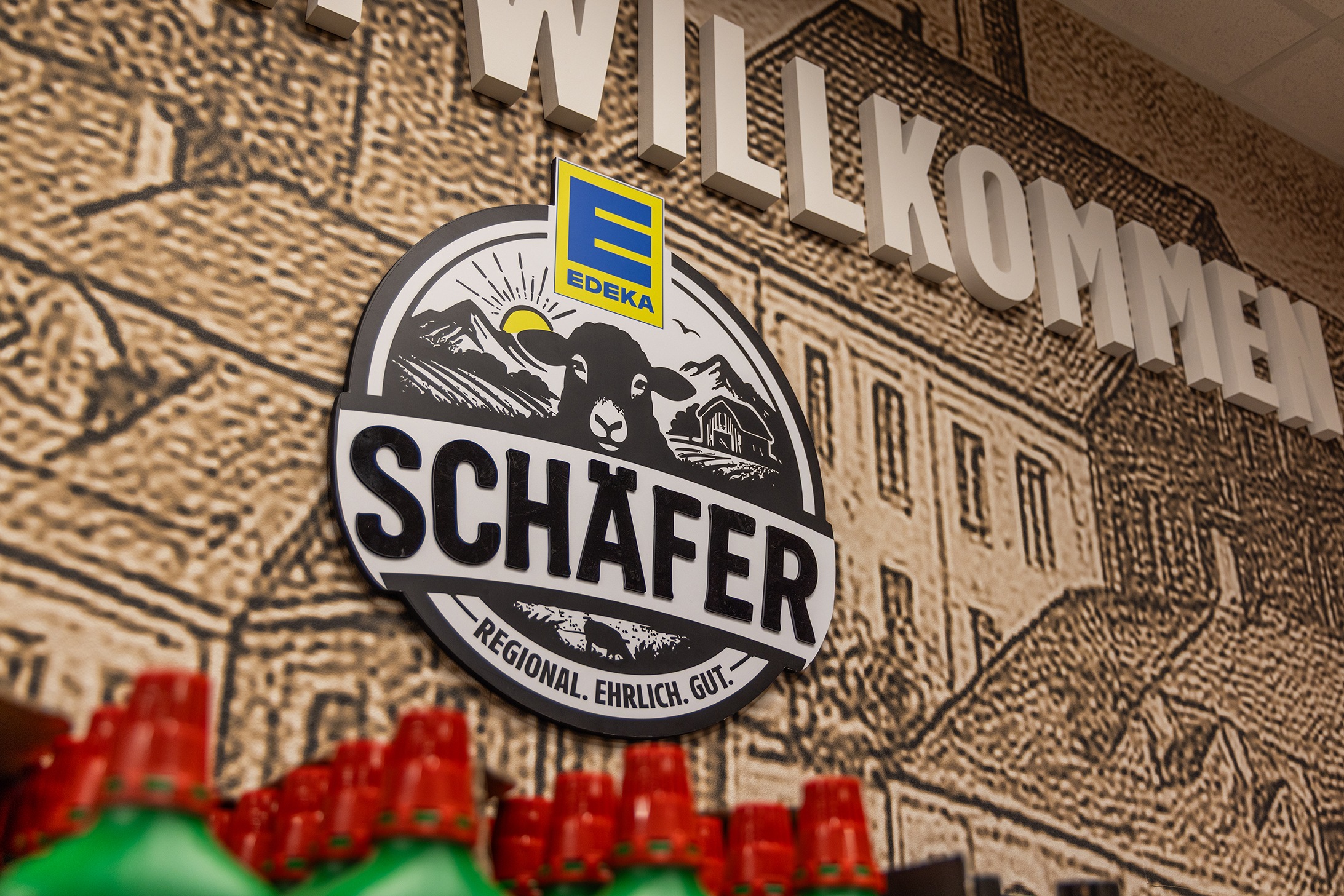 An der Wand hängt das Logo vom EDEKA Schäfer, das ein Schaf mit drin hat.