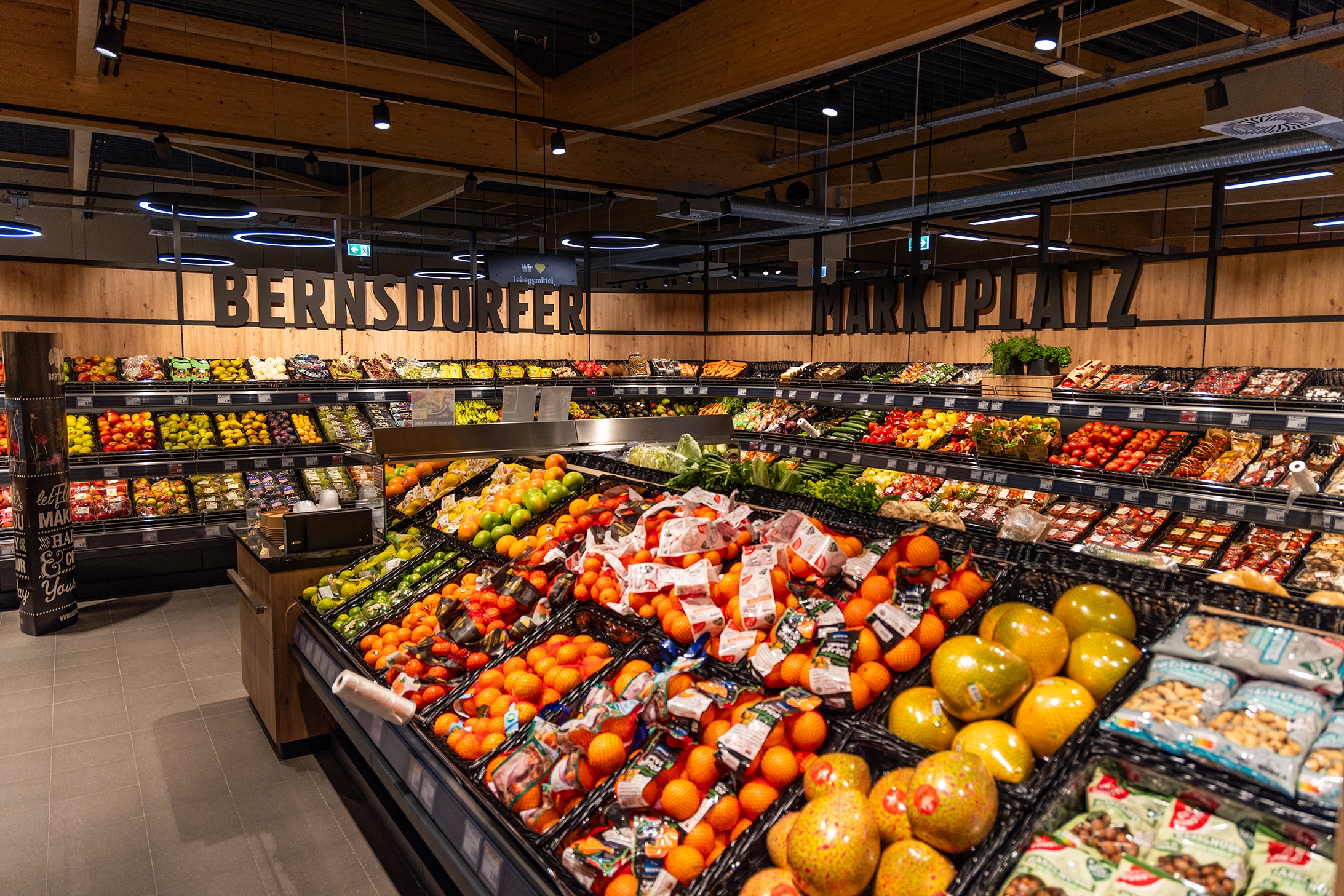 Gesamtüberblick über die Obst- und Gemüseabteilung. An der Wand steht in großen Buchstaben "Bernsdorfer Marktplatz".