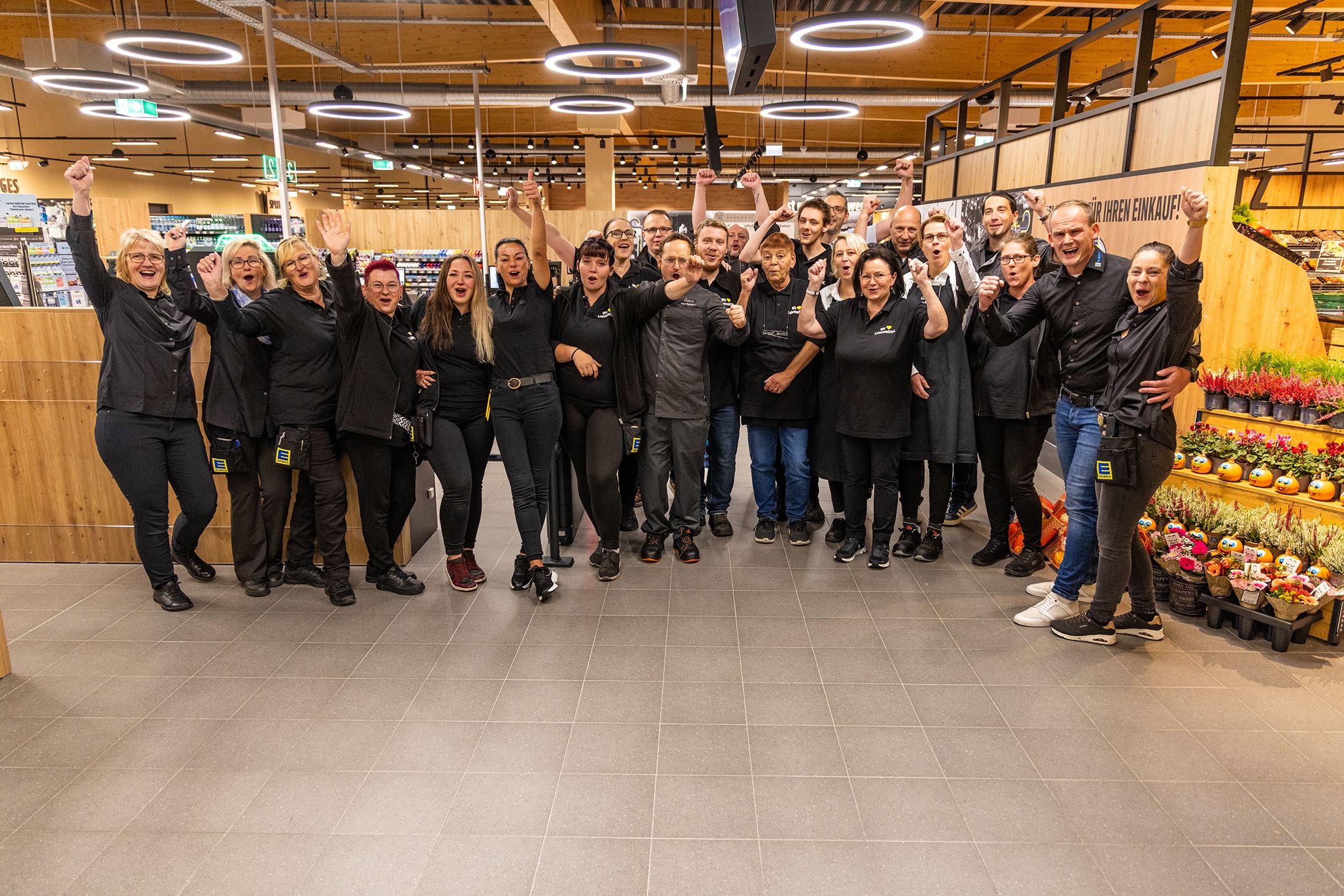 Das ganze Team vom EDEKA Schäfer steht versammelt im Kassenbereich und jubelt.