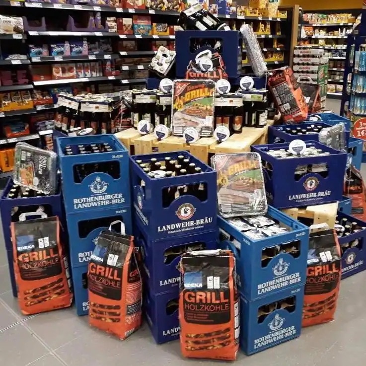 Ein Stand mit verschiedenen Produkten rund ums Grillen auf der Verkaufsfläche eines EDEKA-Marktes.