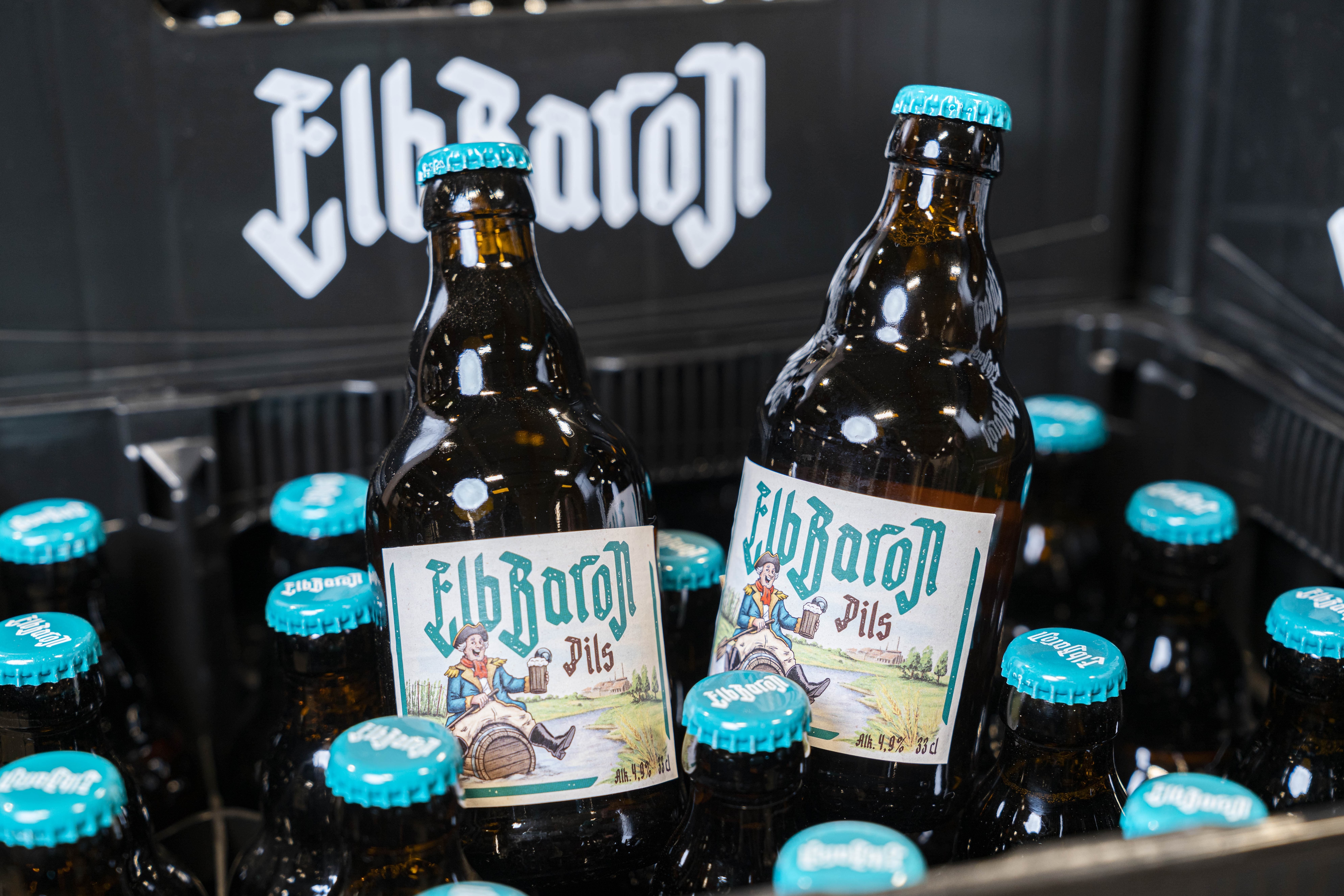 Zwei Flaschen Bier der Marke ElbBaron ragen aus einer schwarzen Bierkiste heraus.