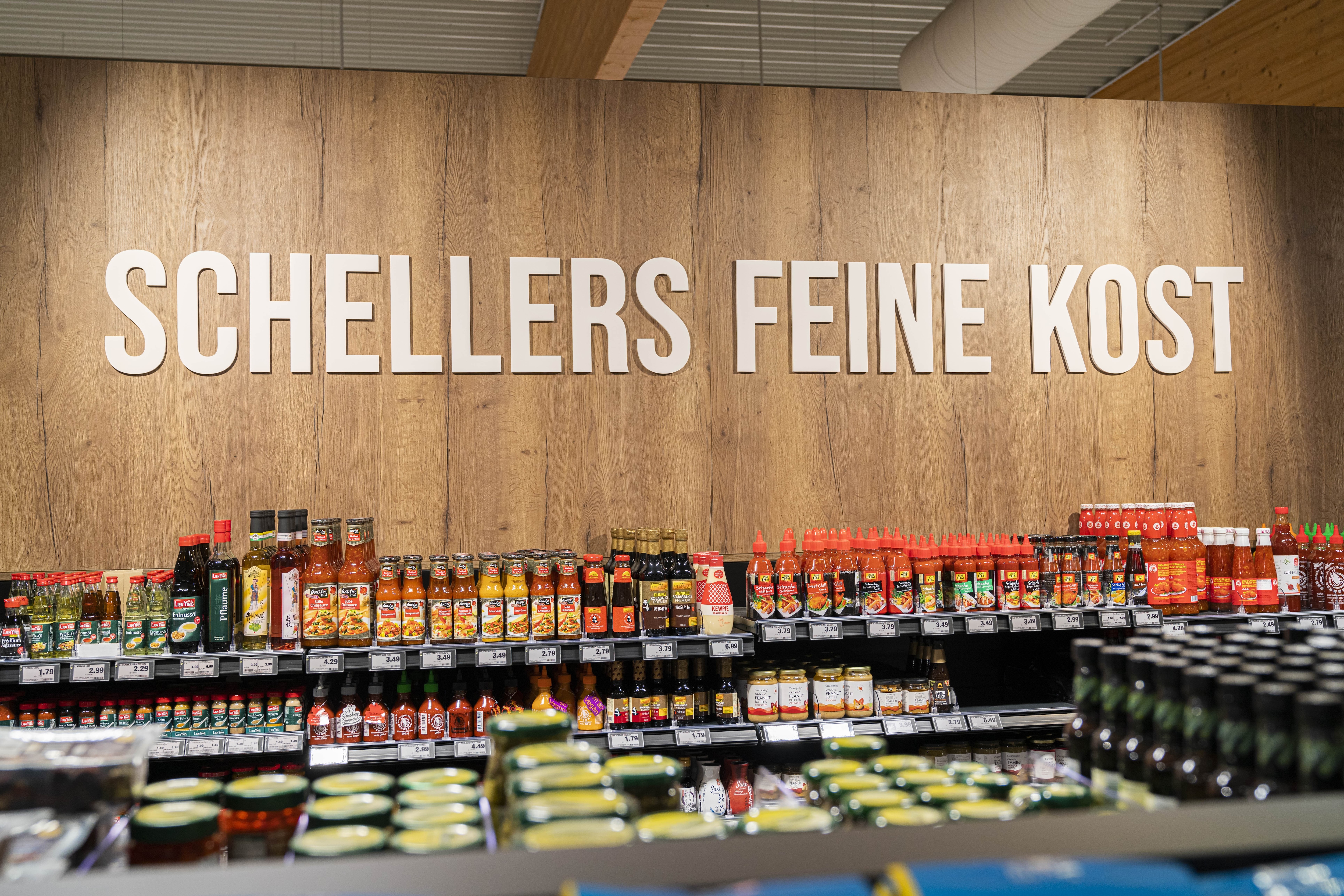 Über einem Regal mit Saucen und Essig steht Schellers feine Kost.