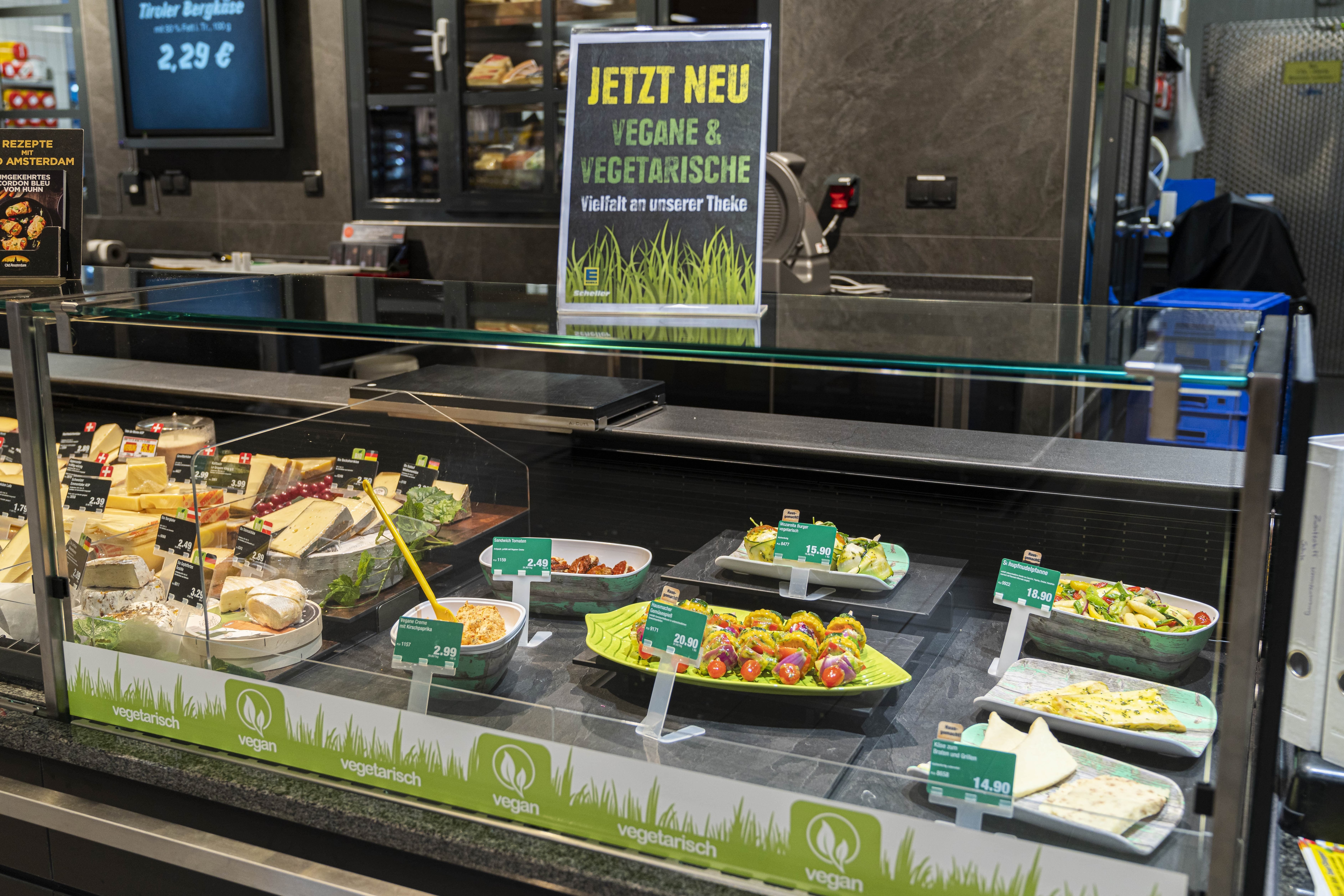 Über dem Käseregal steht ein Schild: Jetzt neu, vegane und vegetarische Vielfalt an unserer Theke.