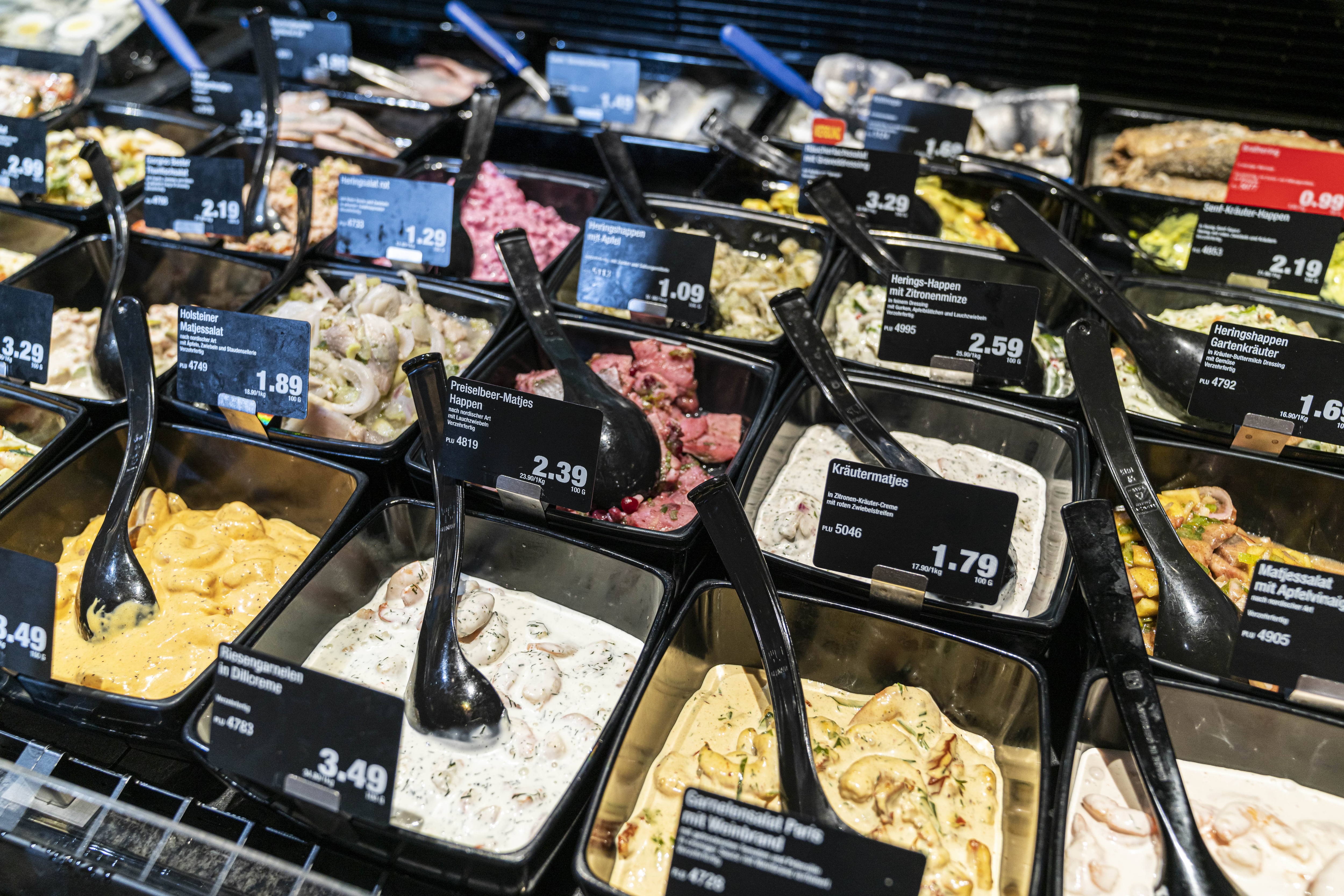 Schwarze Schälchen mit vielen verschiedenen Salaten und Preisschildern.