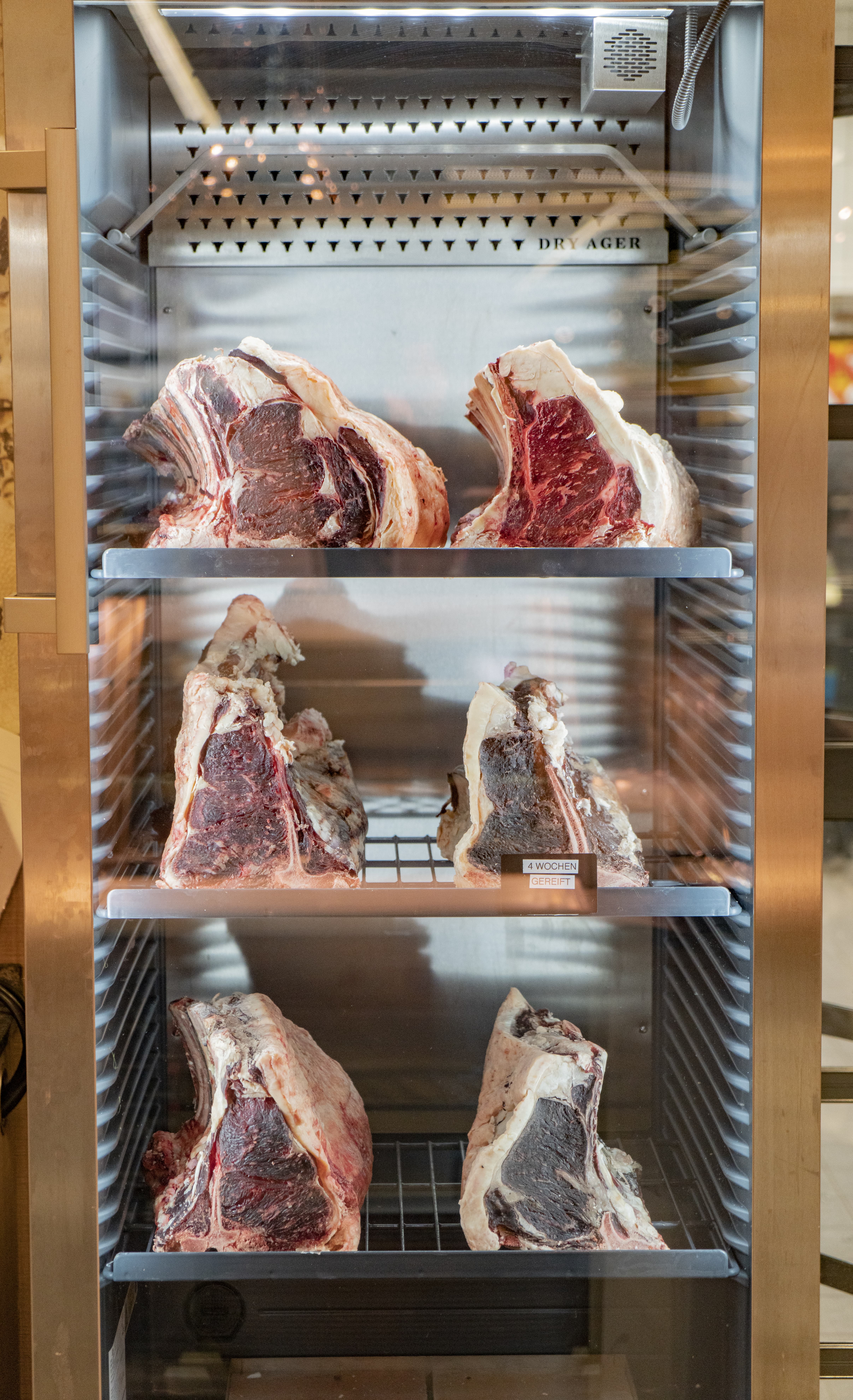 Offener Fleischreifeschrank mit drei Regalstufen.