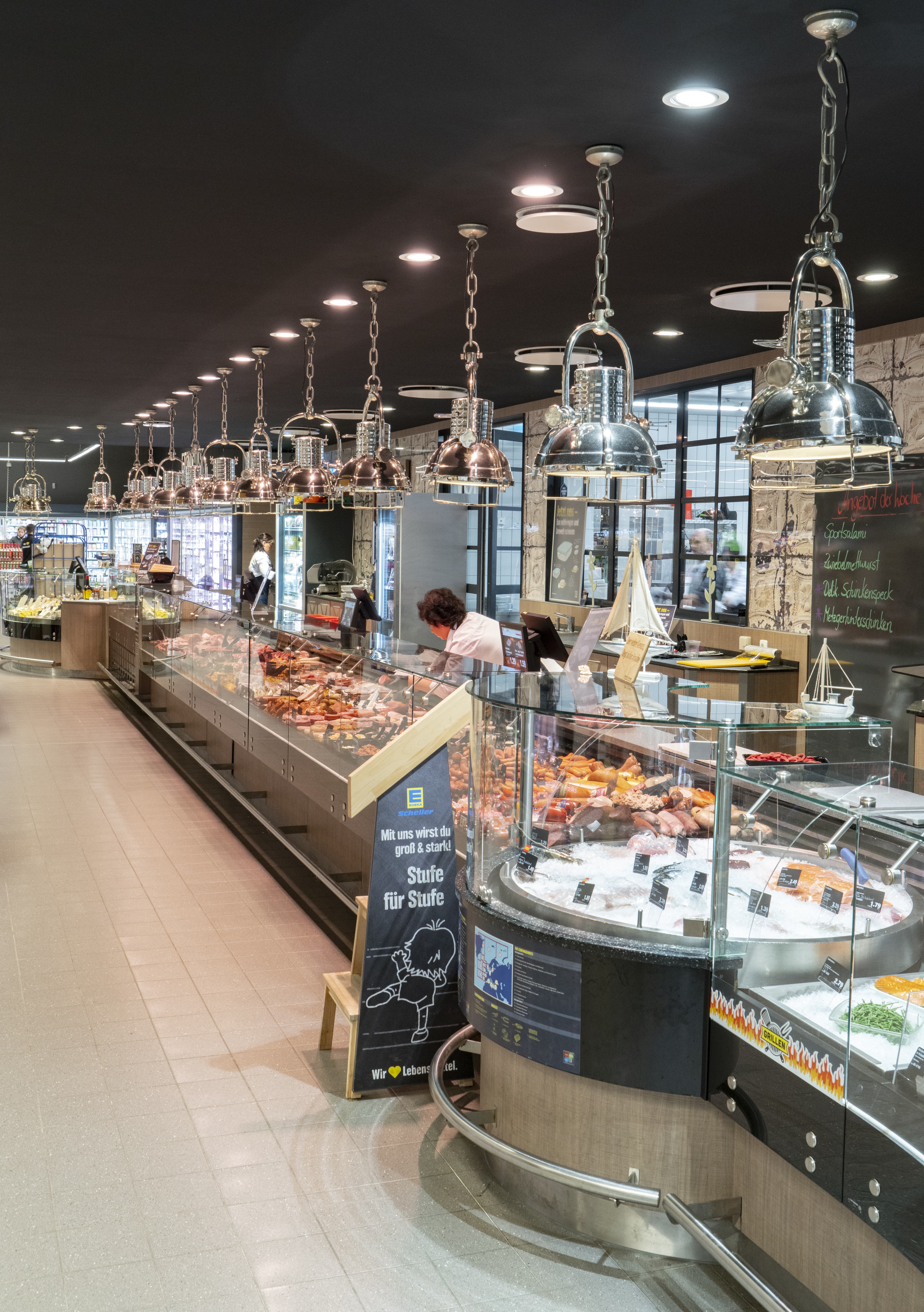 Über der langen Fleischtheke hängen silberne Deckenlampen.