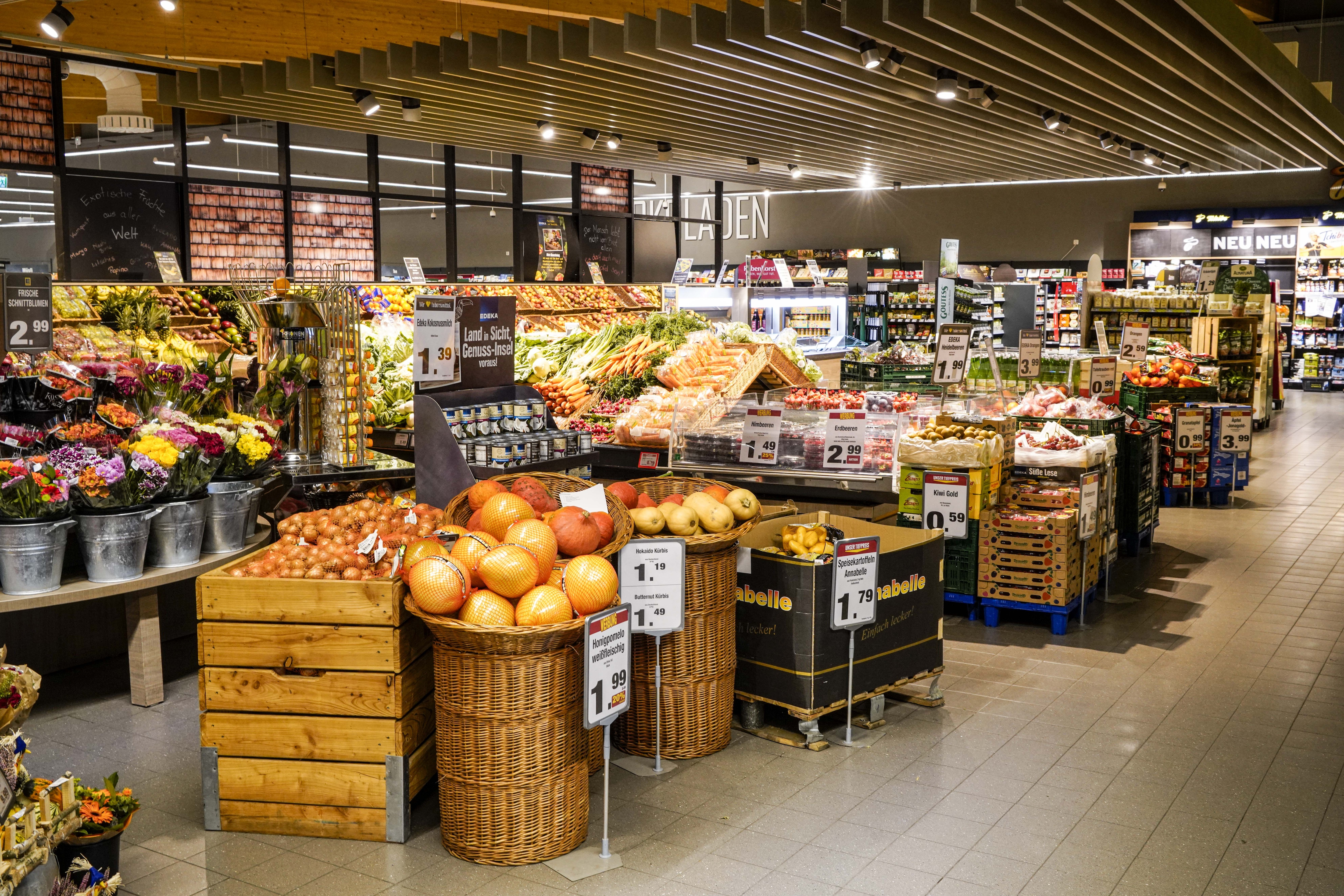 Eingangsbereich des Marktes aus der Totalen mit Blumen und Gemüse.