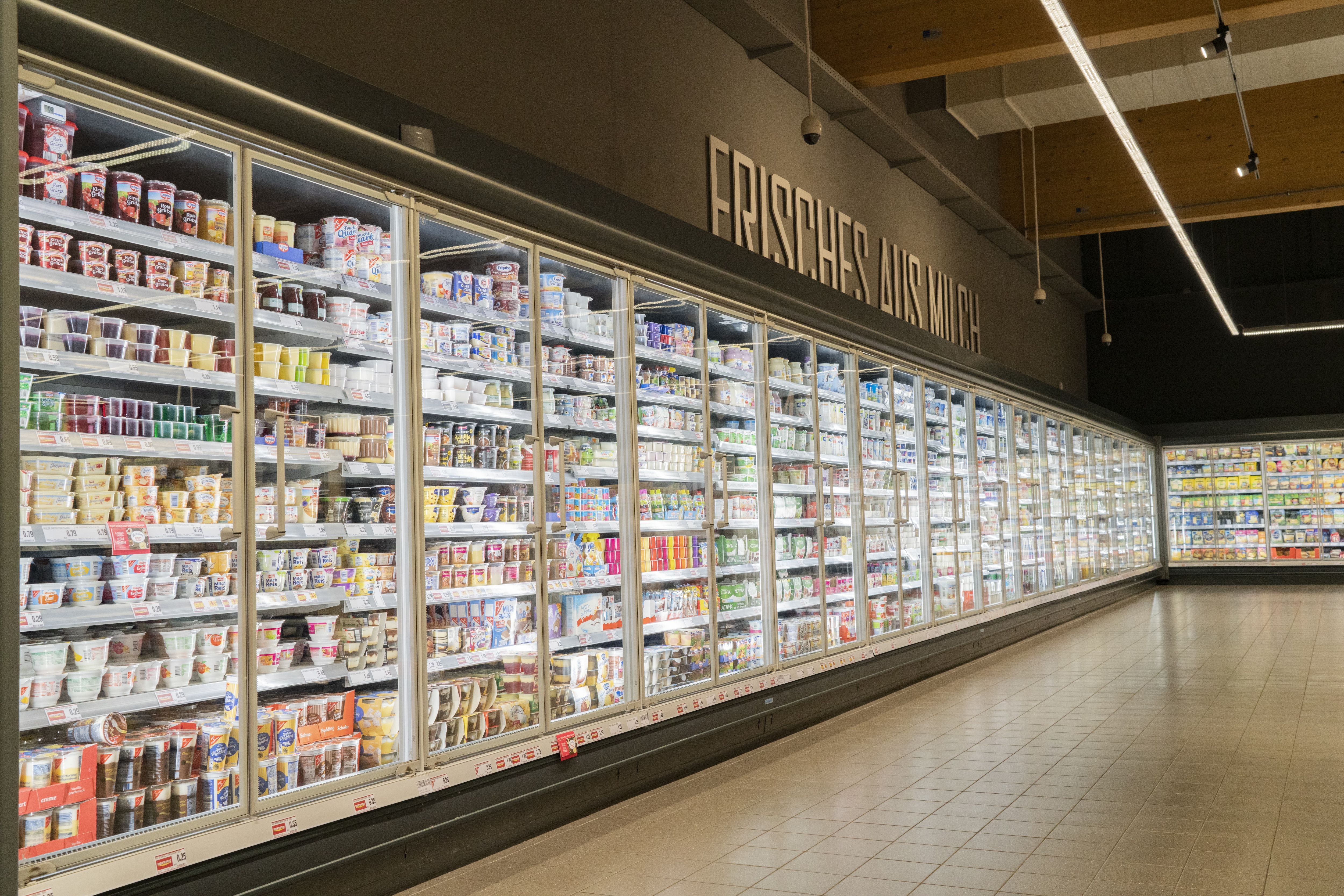 Kühlschränke mit Molkereiprodukten. Darüber steht Frisches aus Milch an der Wand.