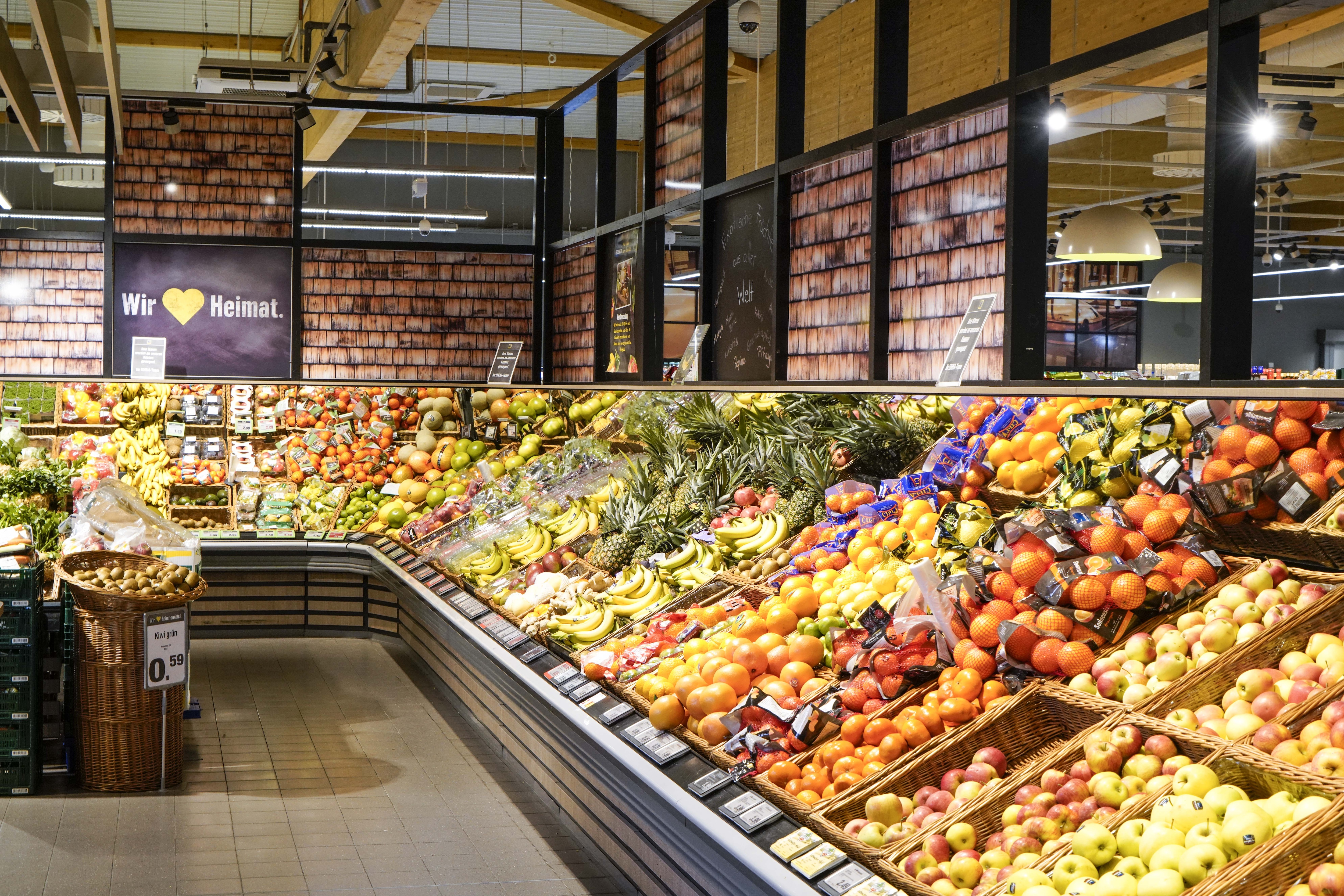 Langes Regal mit Obst wie Äpfeln, Orangen, Bananen und Ananas.