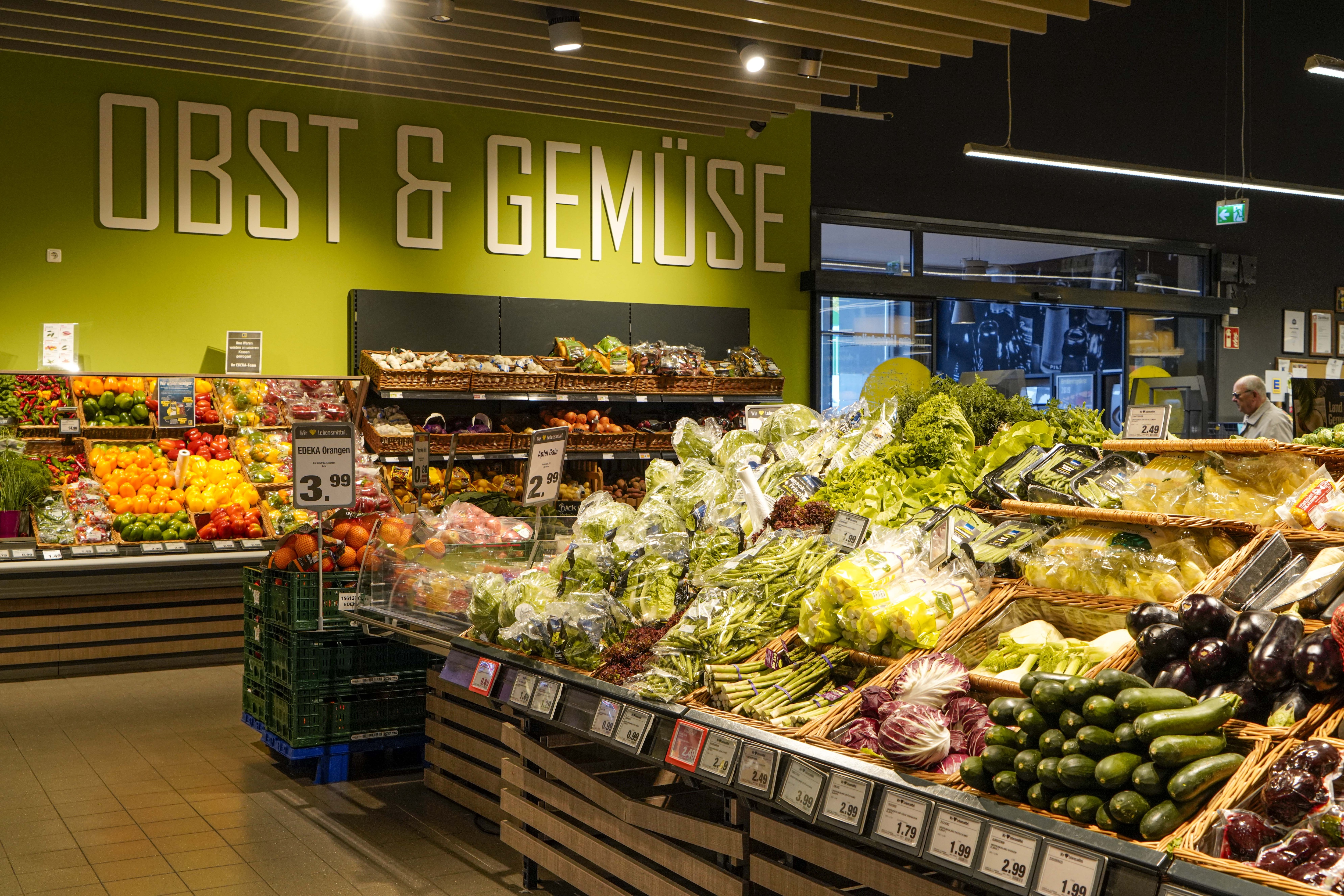 Offene Verkaufsfläche mit Salat und Spargel. An der Wand ein Regal mit Paprika.