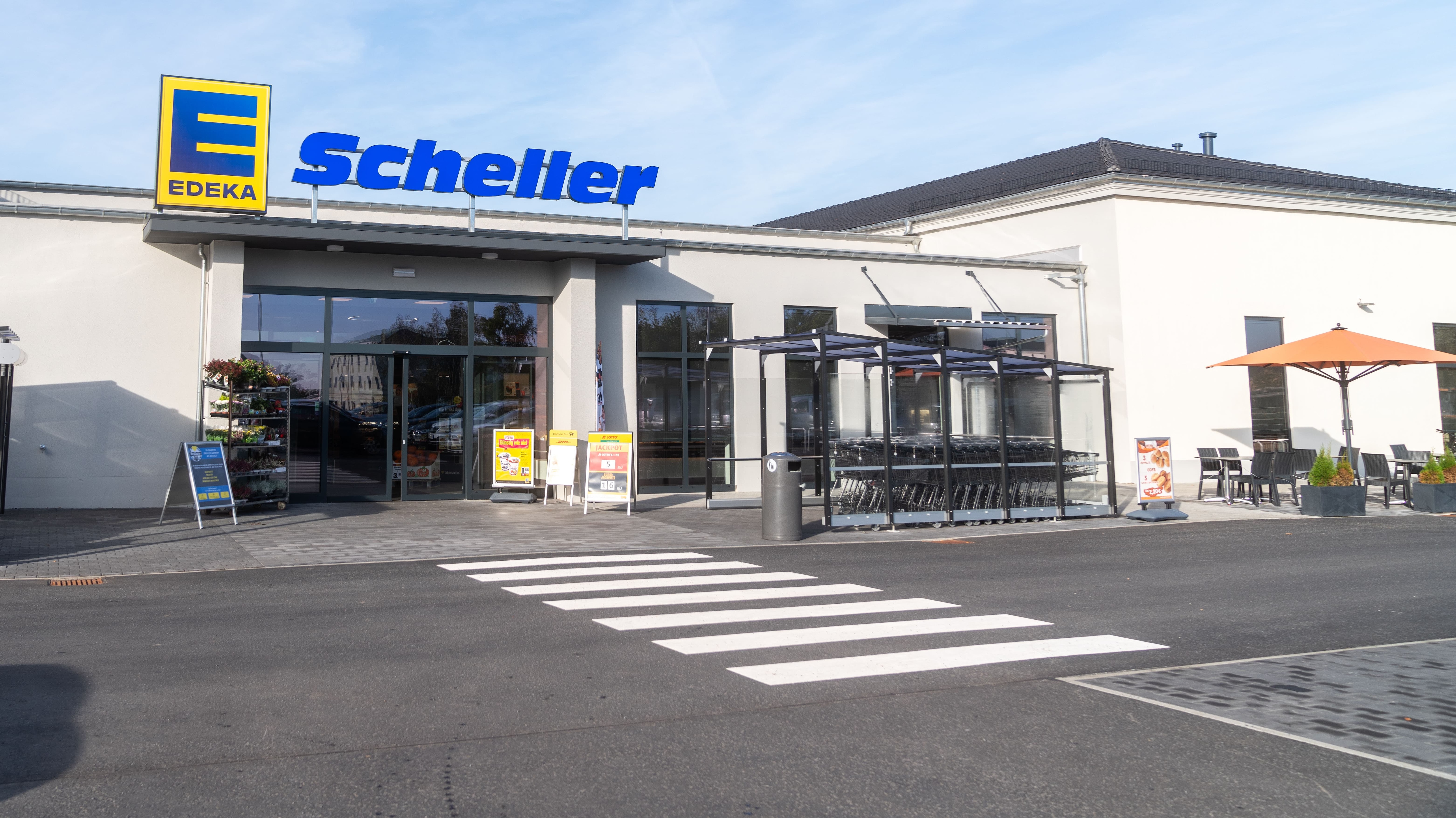 Der Eingang von EDEKA Scheller vom Parkplatz aus gesehen. Vor dem Eingang ist ein Zebratsreifen.