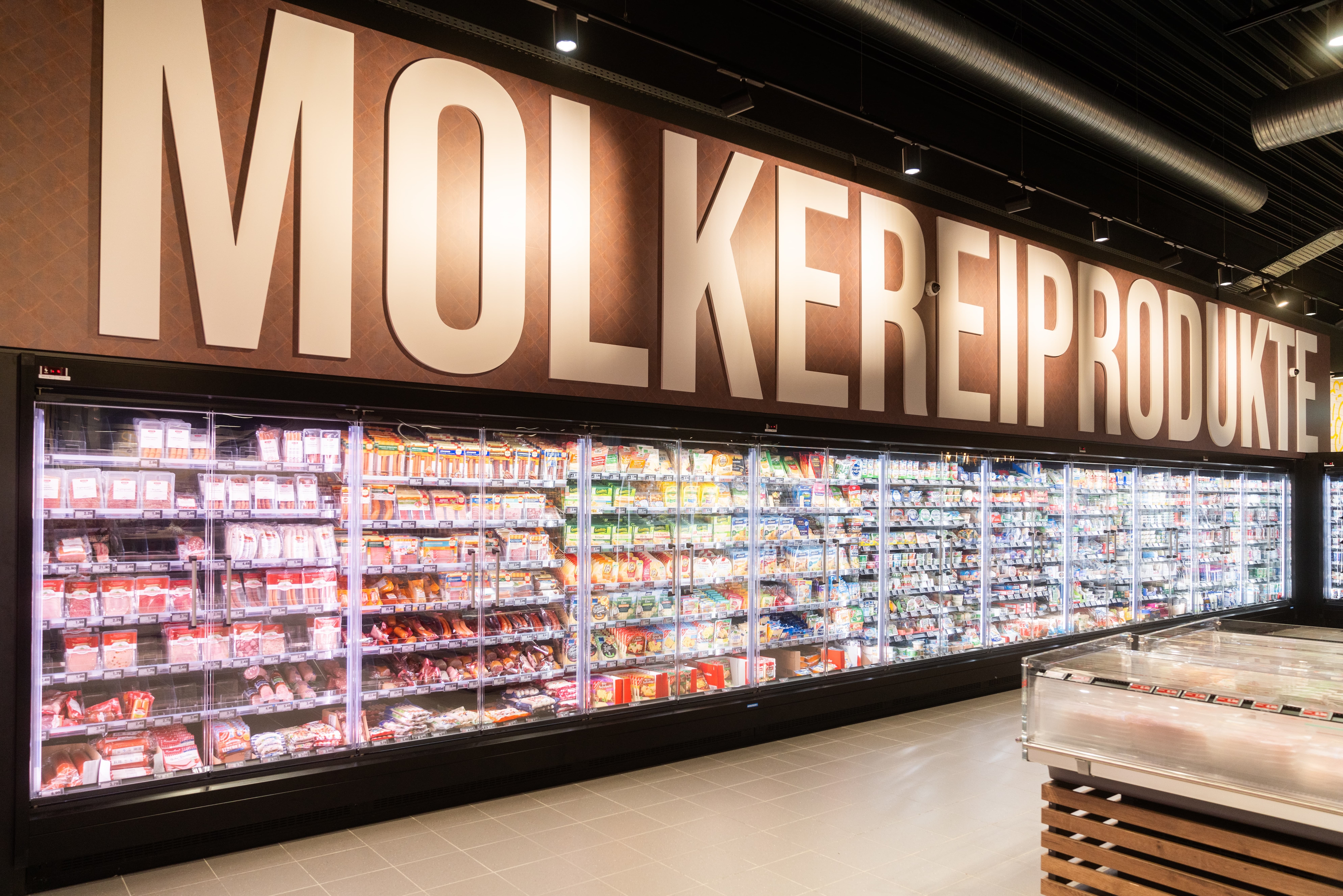 Über einem Gang mit Kühlschränken steht in Leuchtbuchstaben Molkereiprodukte.