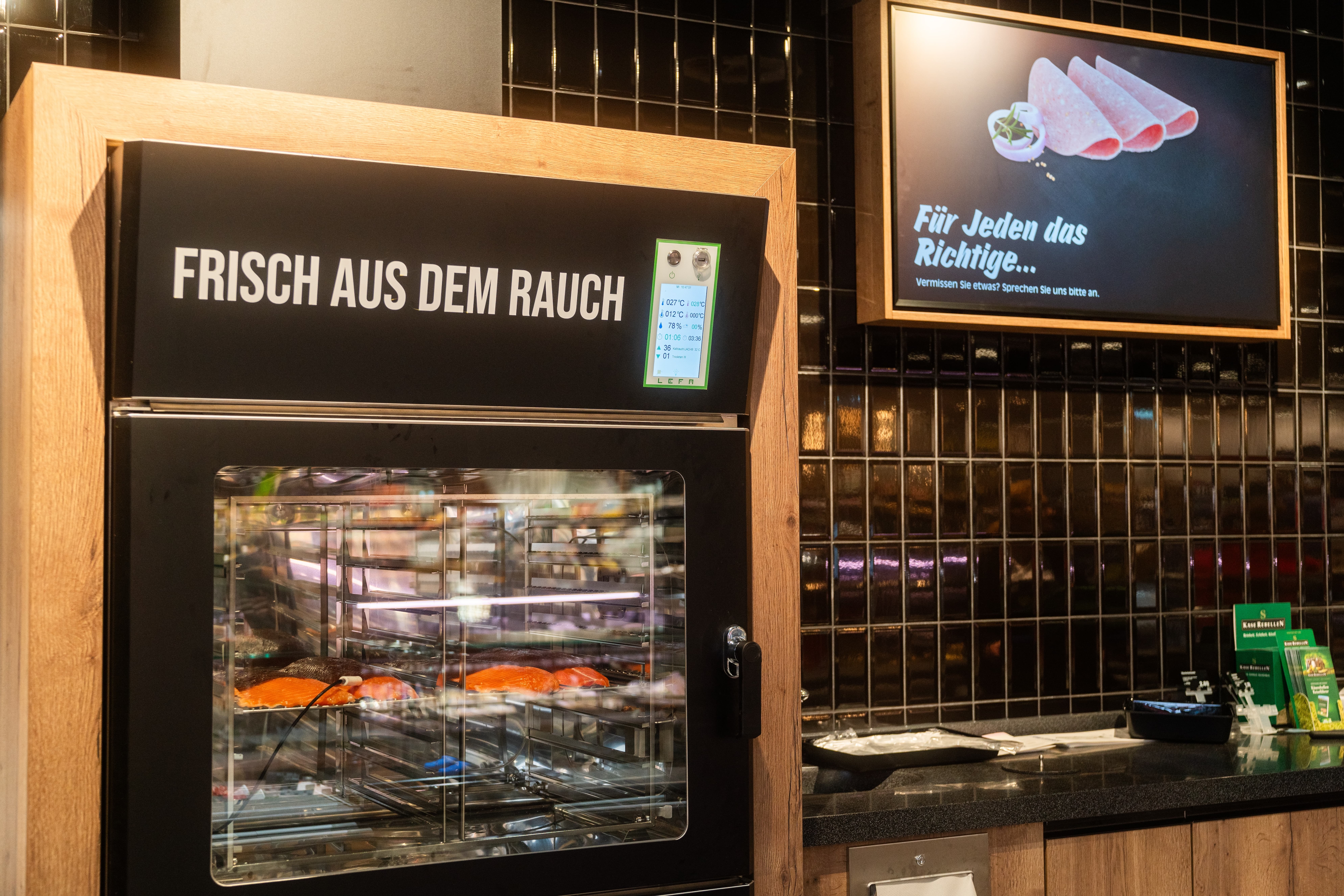 Über einem Schrank mit Glastür steht Frisch aus dem Rauch. Im Inneren liegen Fischfilets.