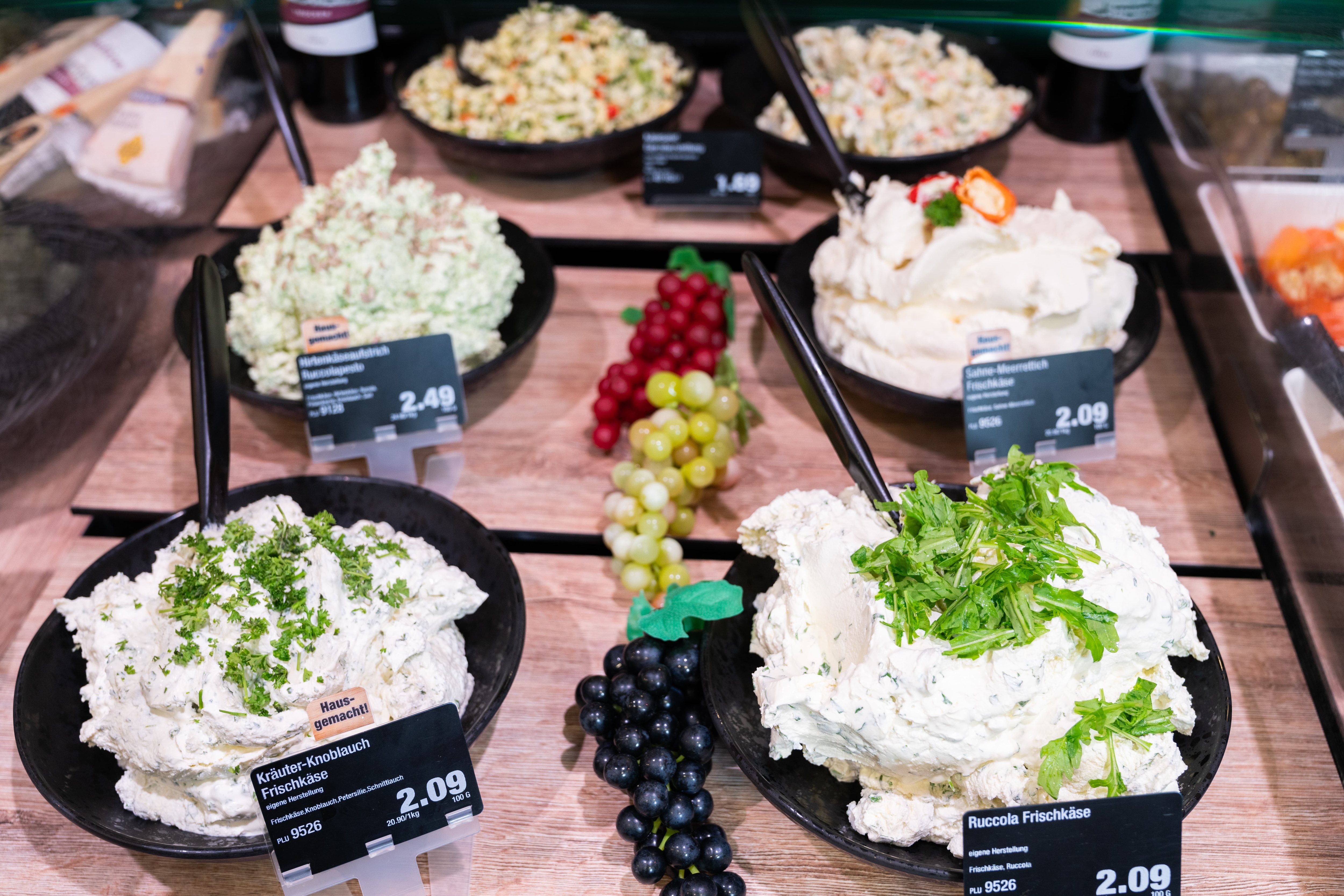 Schwarze Teller mit verschiedenen Sorten Frischkäse und Preisschildern.