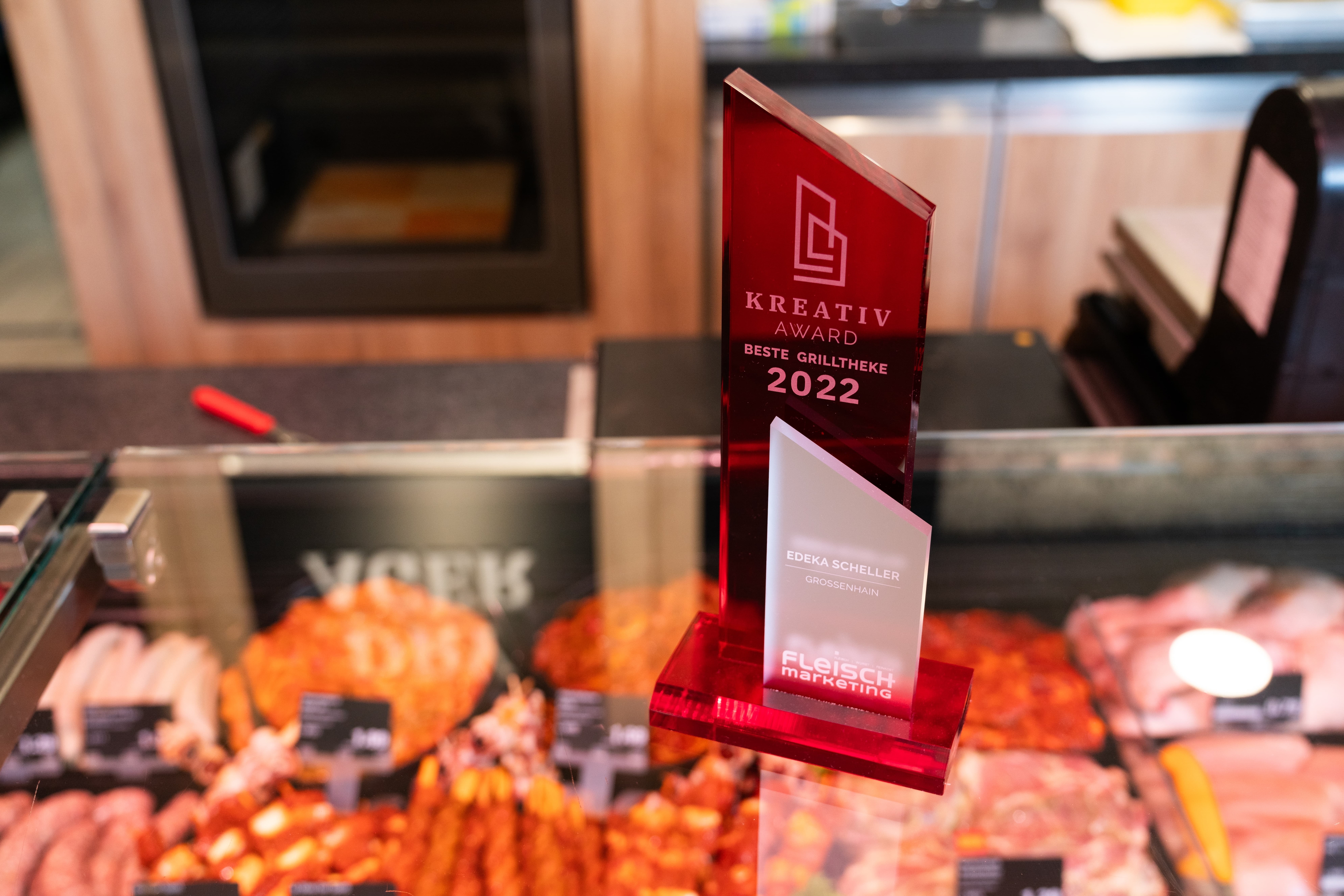 Rote Glastrophäe steht auf der Frischetheke. Inschrift: Kreativ Award beste Grilltheke 2022.
