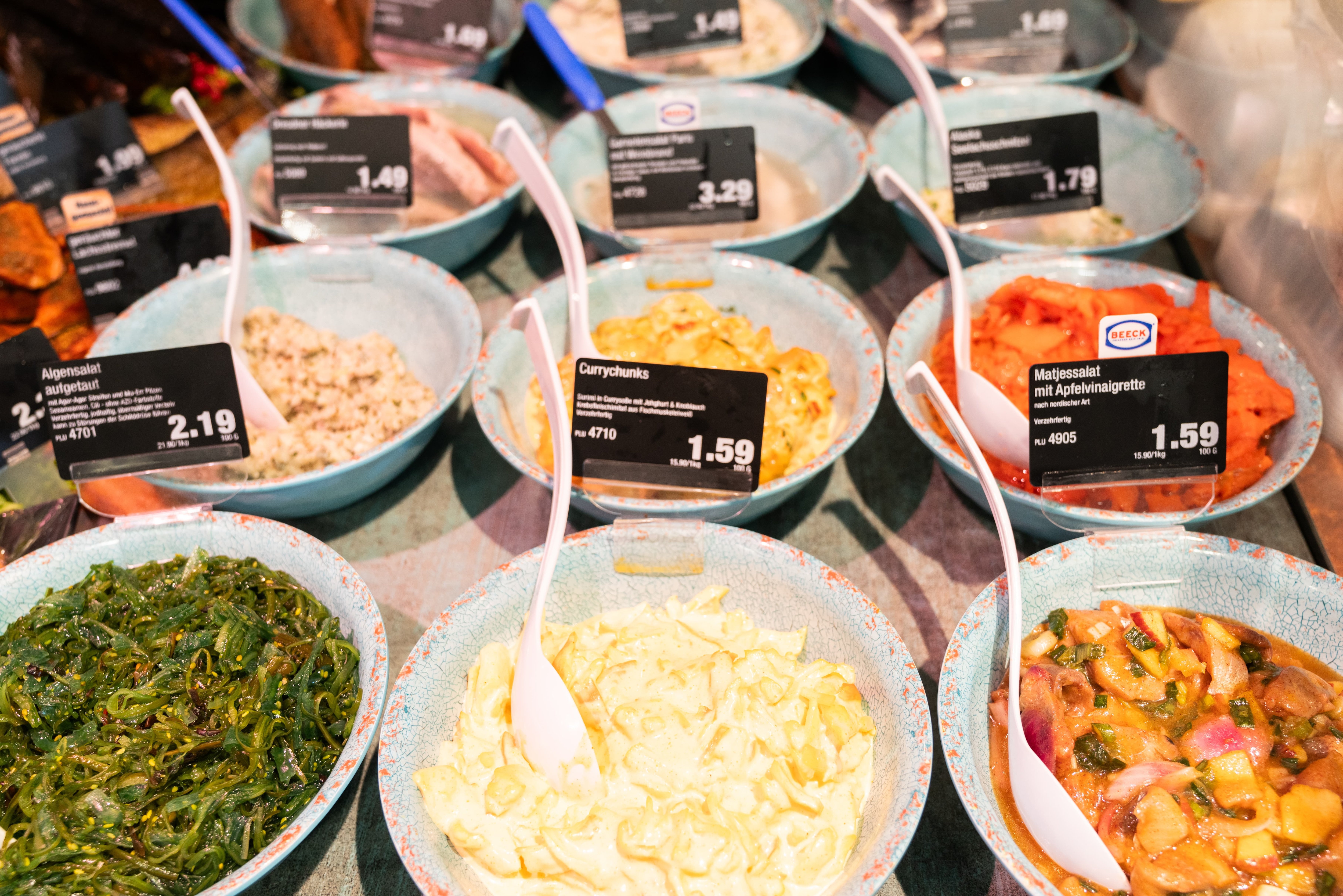 Salate in Schälchen mit Preisschildern.