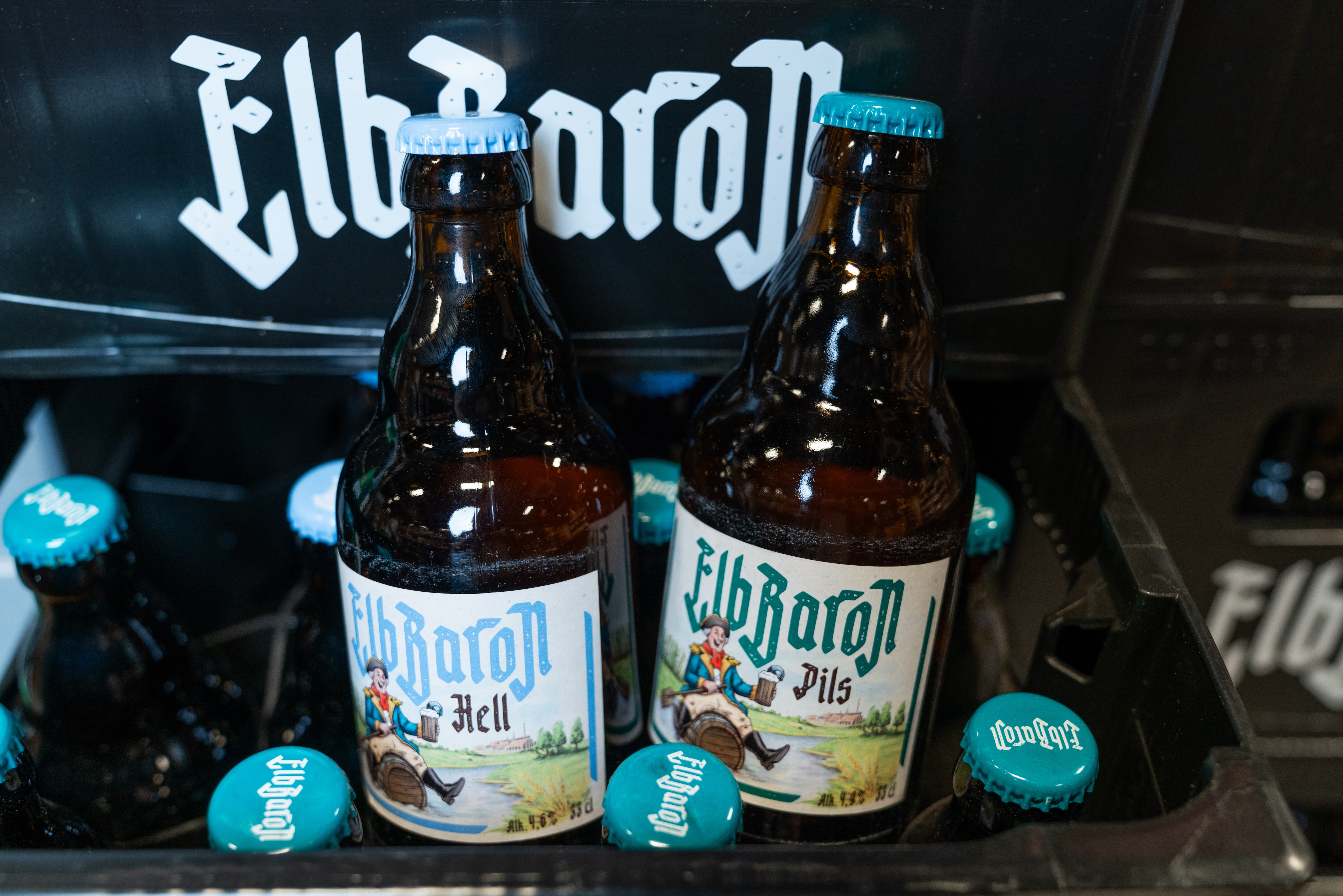 Zwei Flaschen Bier der Marke ElbBaron ragen aus einer schwarzen Bierkiste heraus.