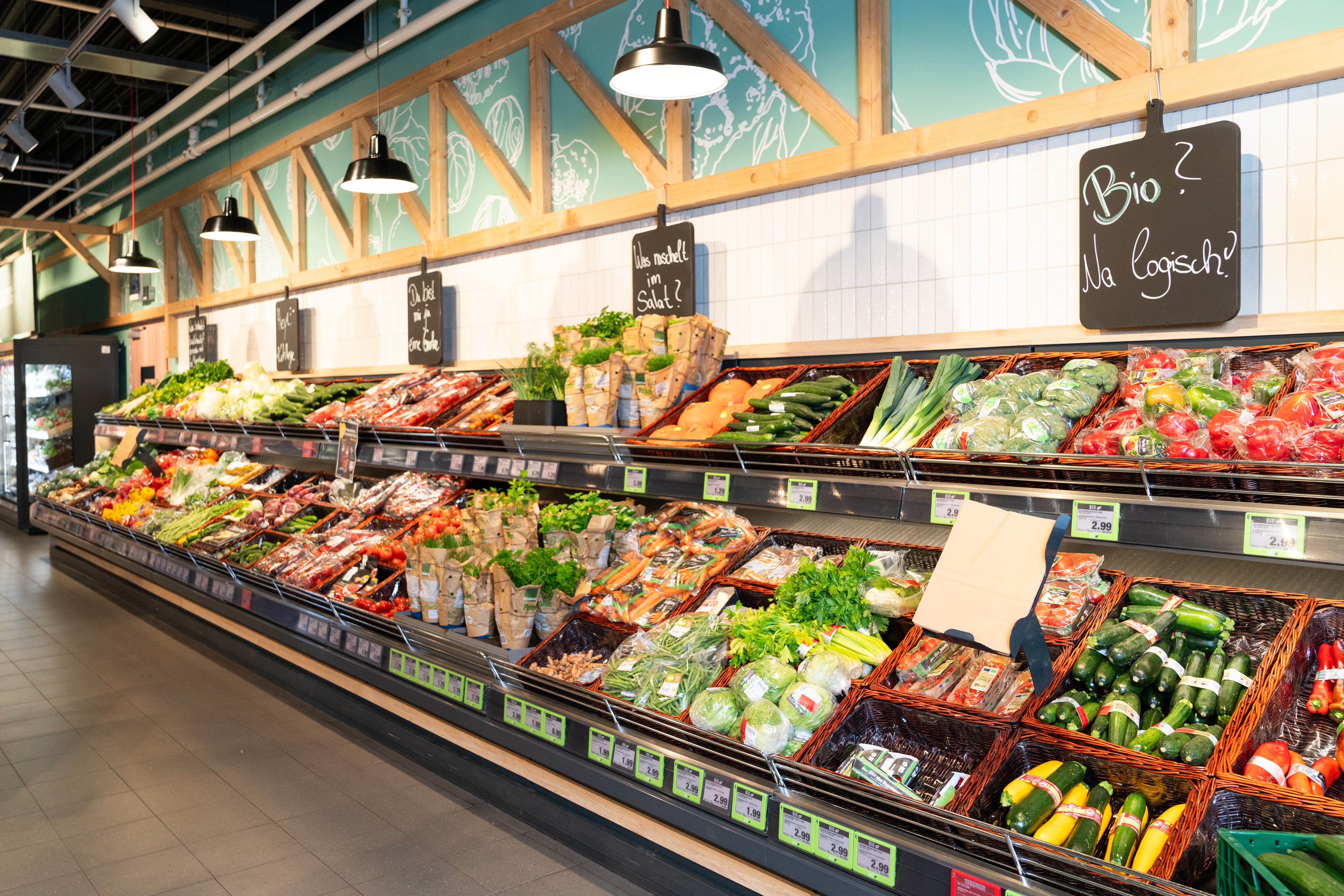 Über dem Gemüseregal hängt eine schwarze Tafel, auf der geschrieben steht: Bio? Na logisch!