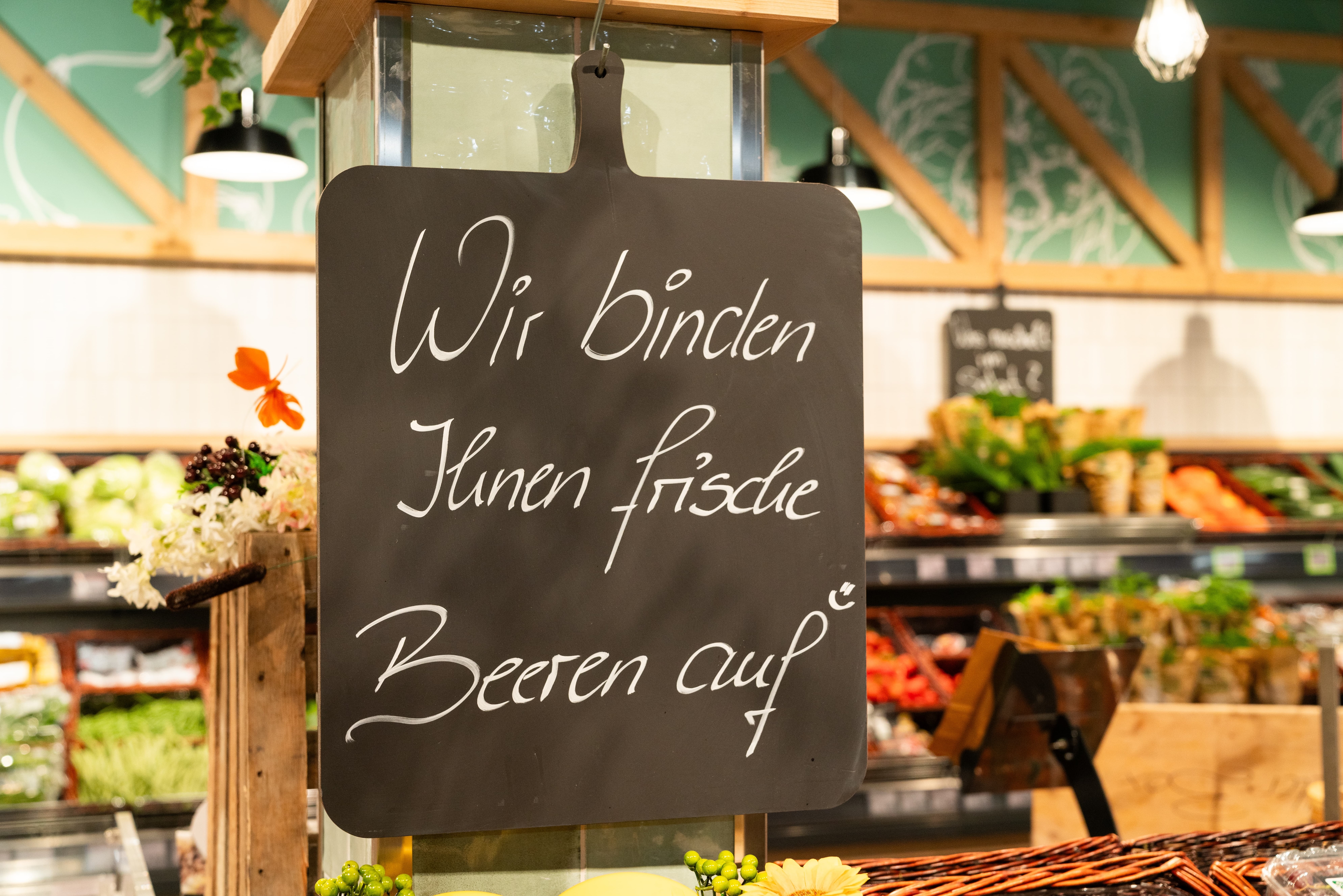 Auf einem schwarzen Brett steht: Wir binden Ihnen frische Beeren auf.