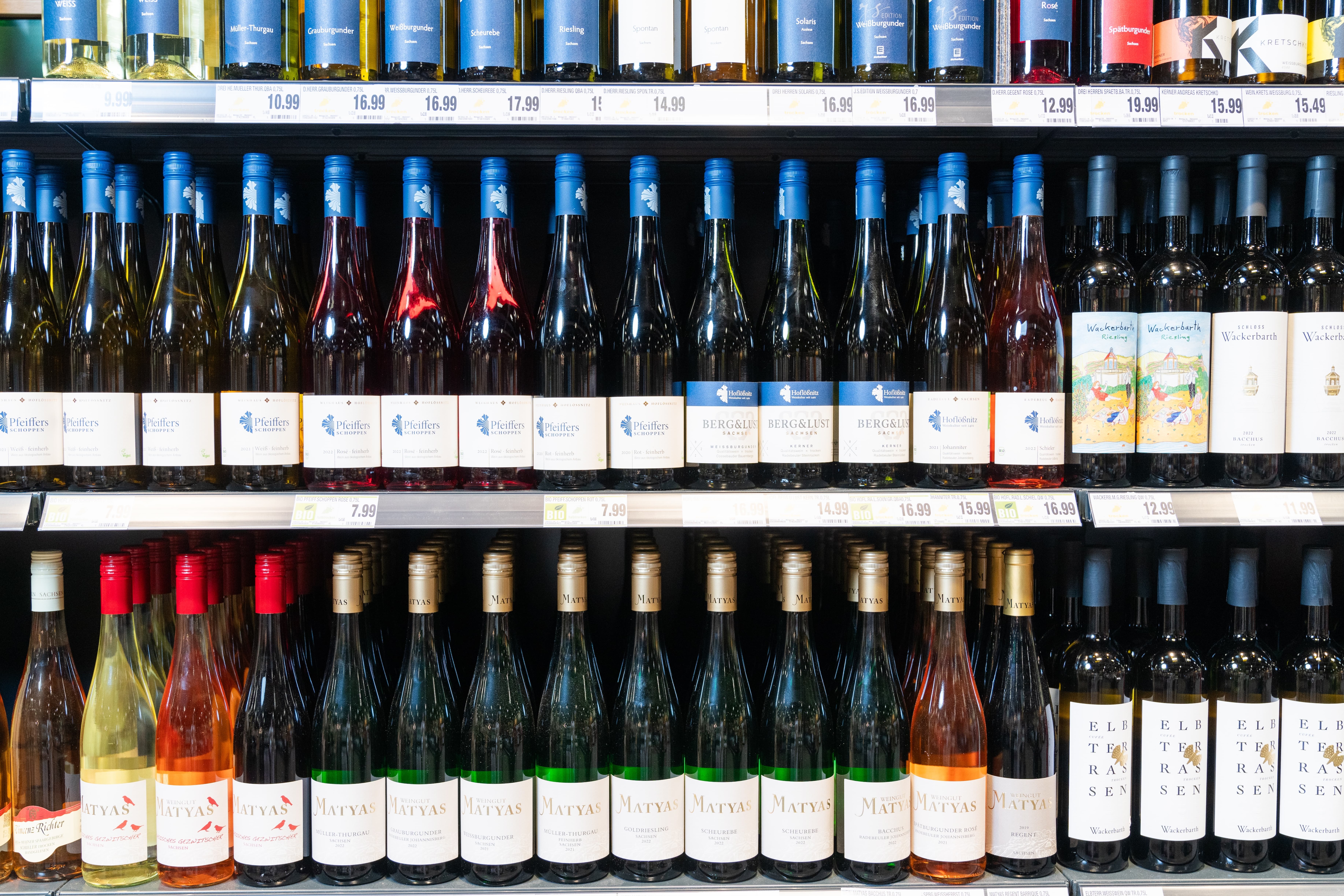 Drei Regale mit verschiedenen Weinflaschen.