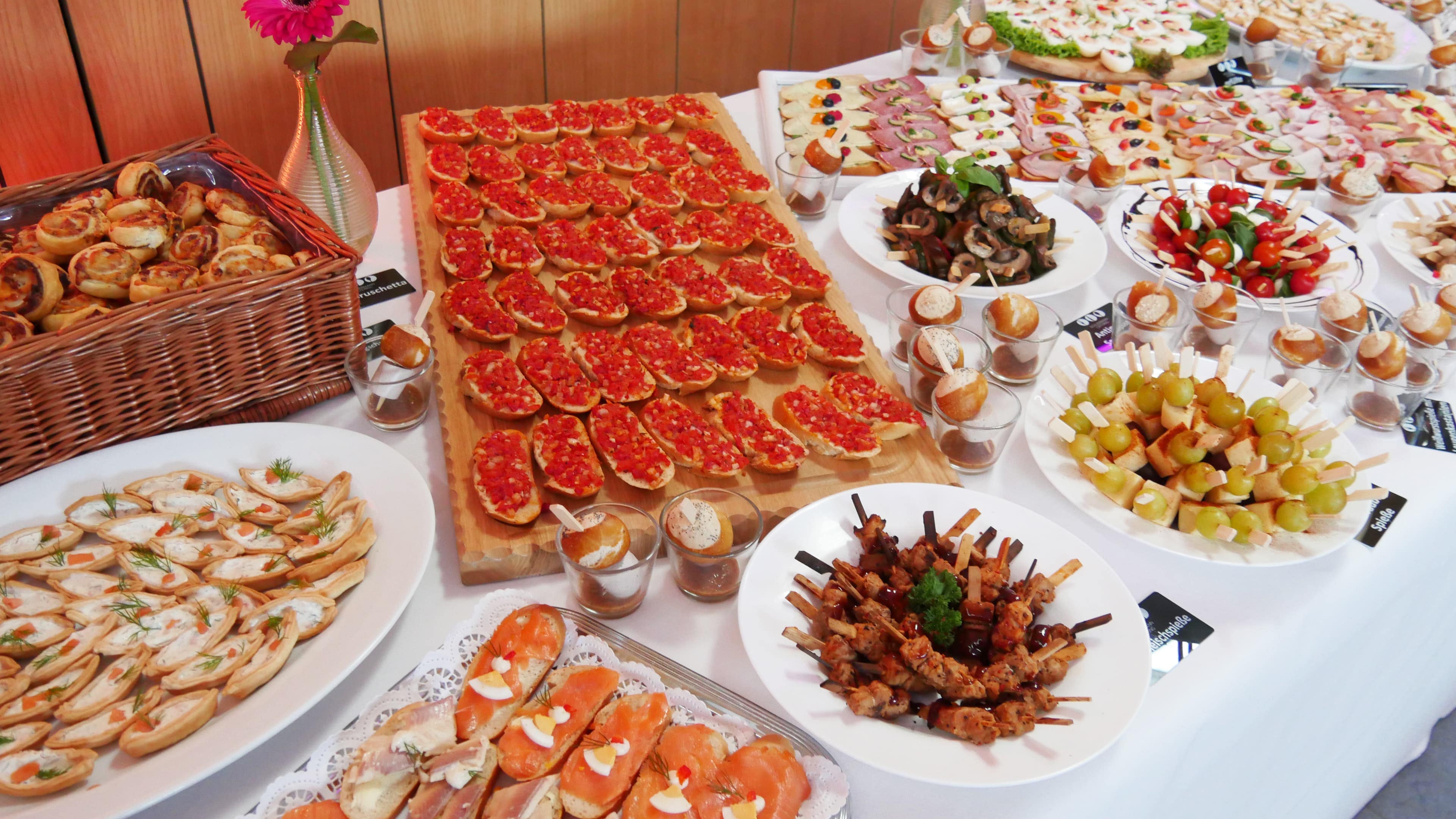 Ein reich gedecktes Buffet mit verschiedensten Sorten Fingerfood, darunter belegte Schnittchen, Brötchen, Spieße.