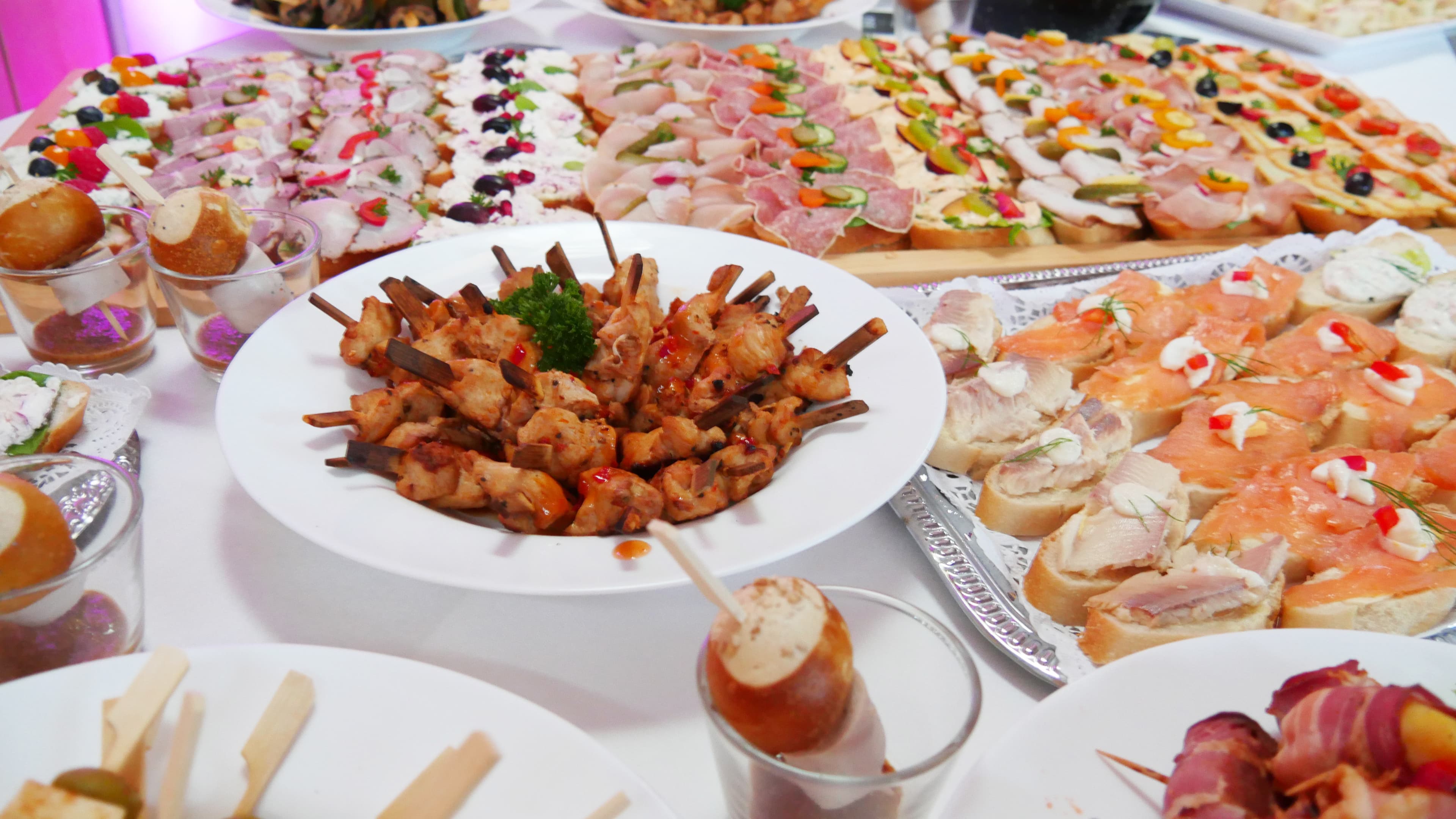 Ein reich gedecktes Buffet mit verschiedensten Sorten Fingerfood, darunter belegte Schnittchen, Brötchen, Spieße.