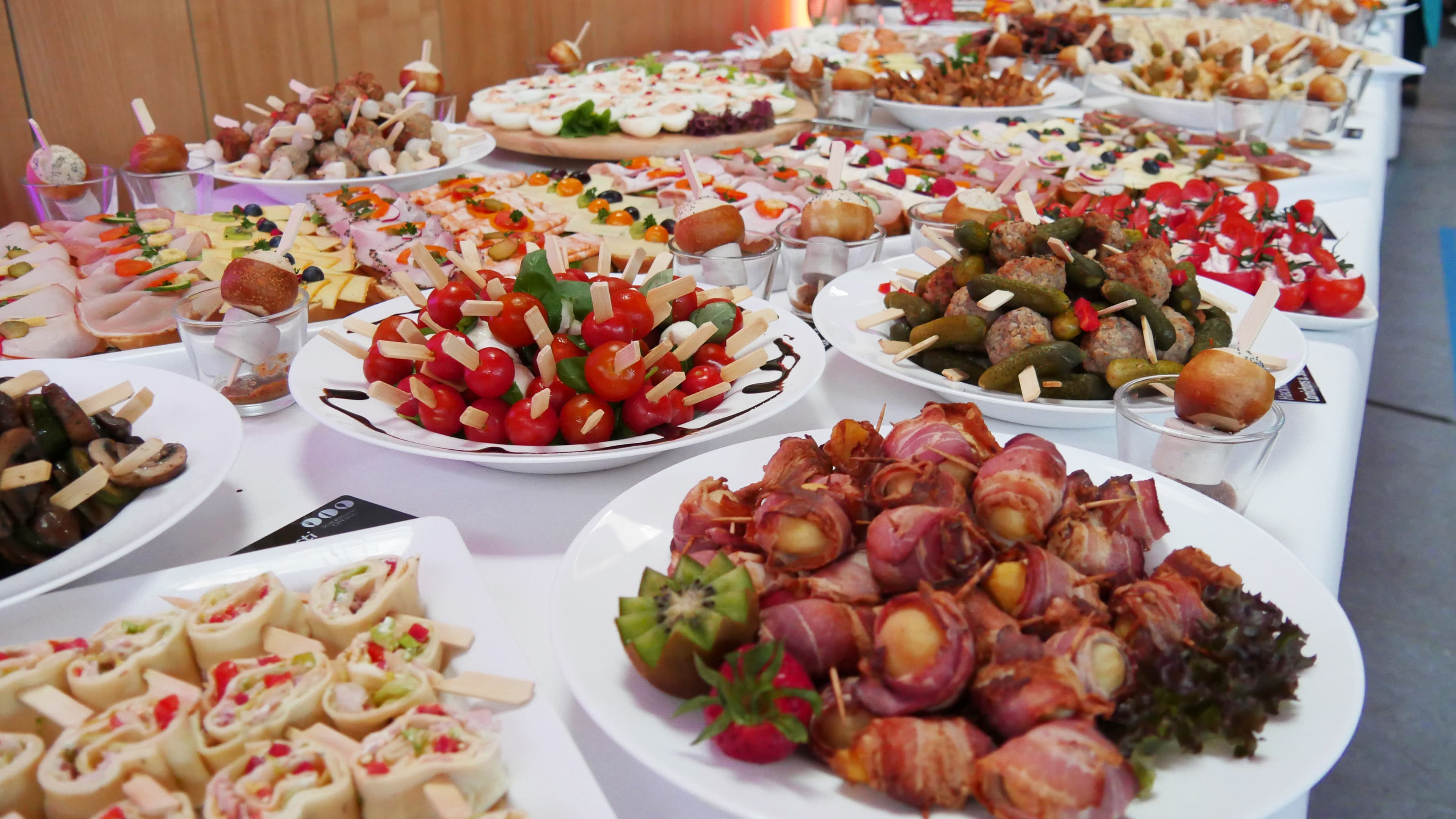 Ein reich gedecktes Buffet mit verschiedensten Sorten Fingerfood, darunter belegte Schnittchen, Brötchen, Spieße.