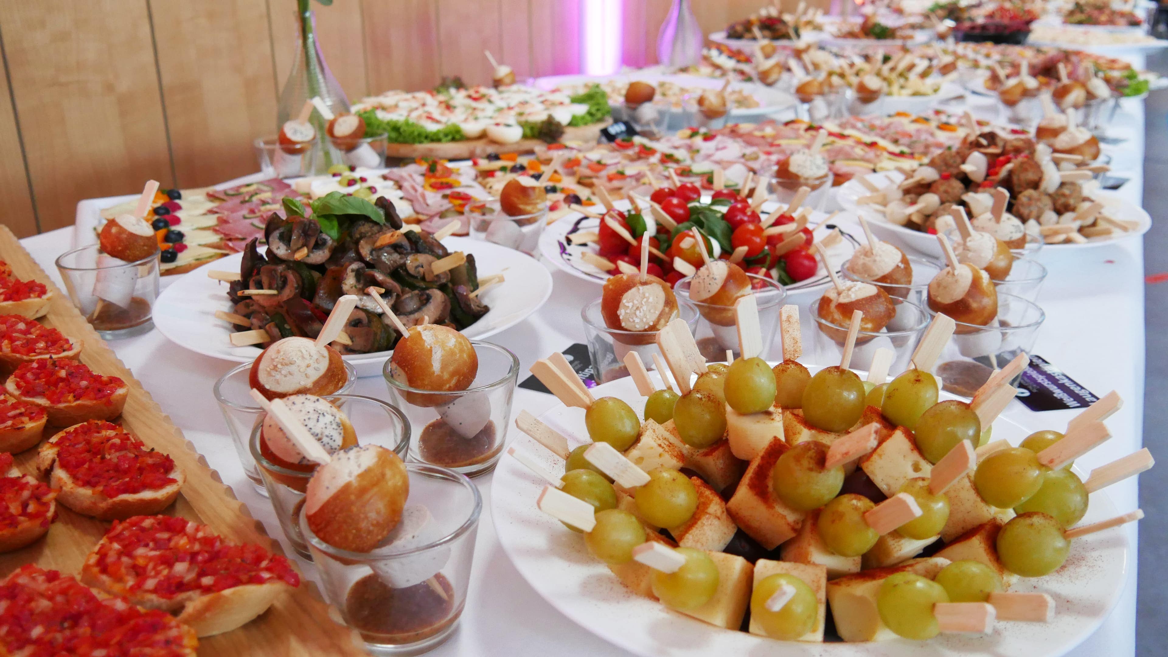 Ein reich gedecktes Buffet mit verschiedensten Sorten Fingerfood, darunter belegte Schnittchen, Brötchen, Spieße.
