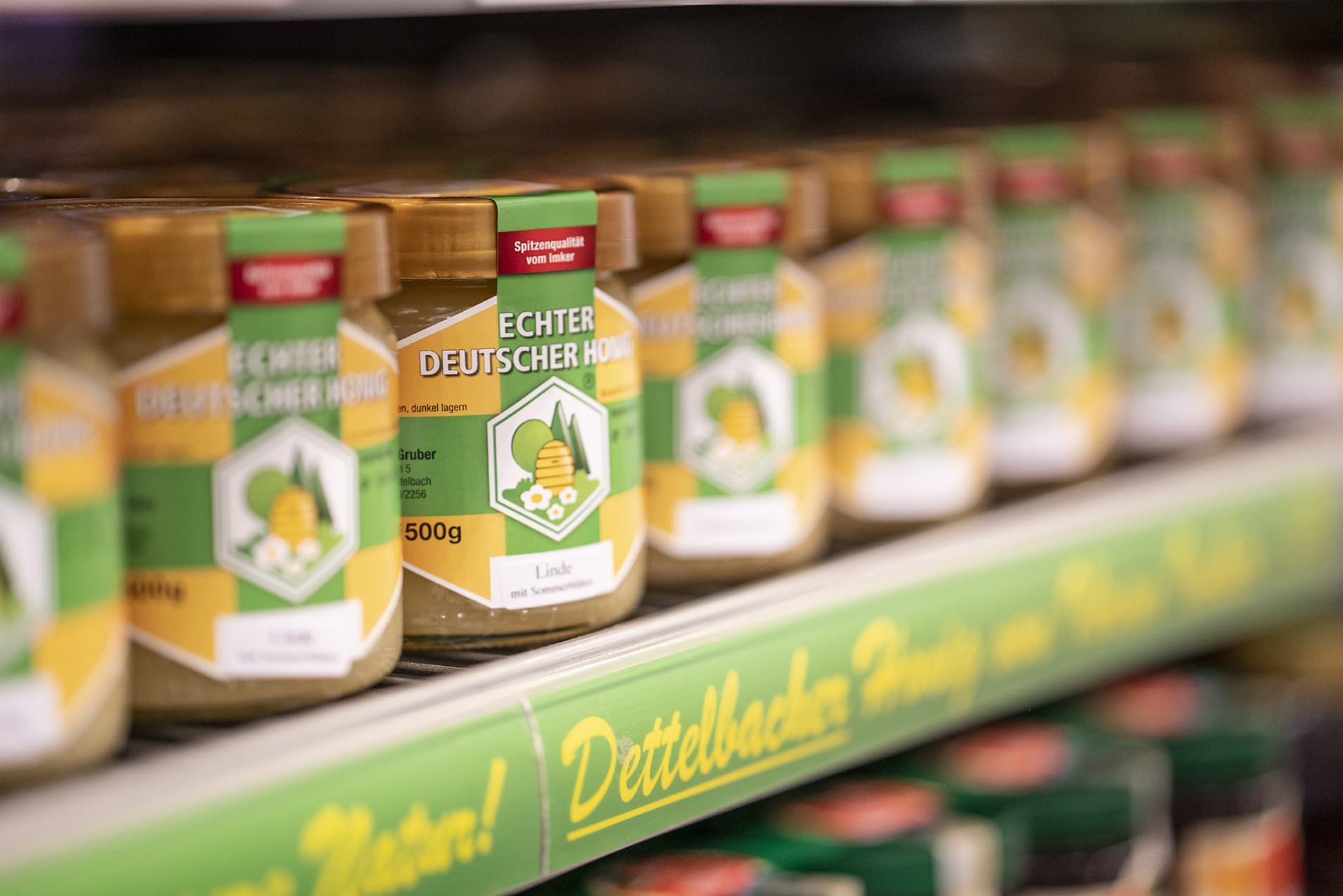 Close-Up einer Regalreihe mit regionalem Honig mit gelb-grünen Etiketten.