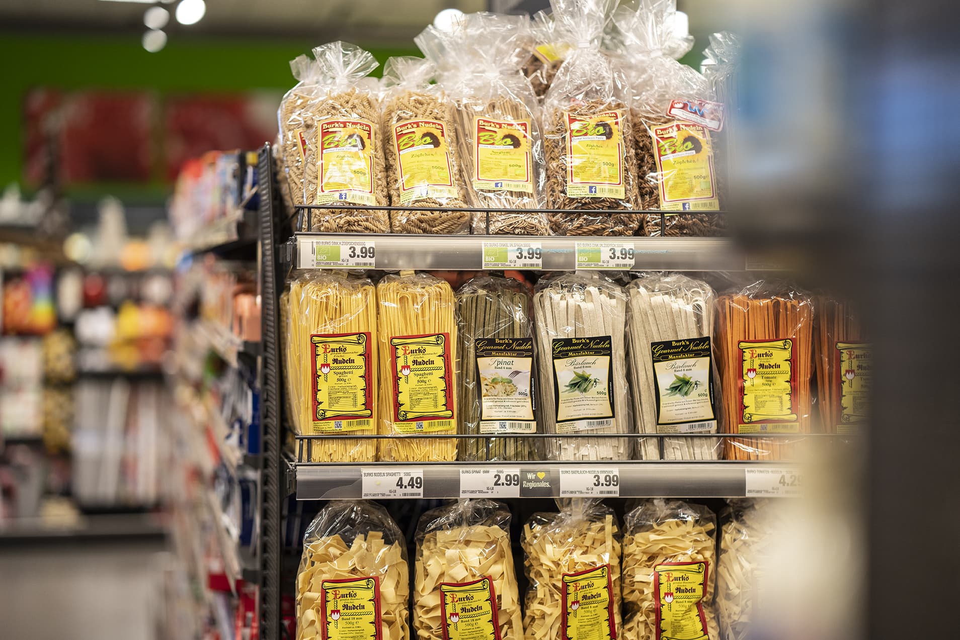 Ein Regal mit verschiedenen regionalen Nudelsorten, daneben ein Gang.