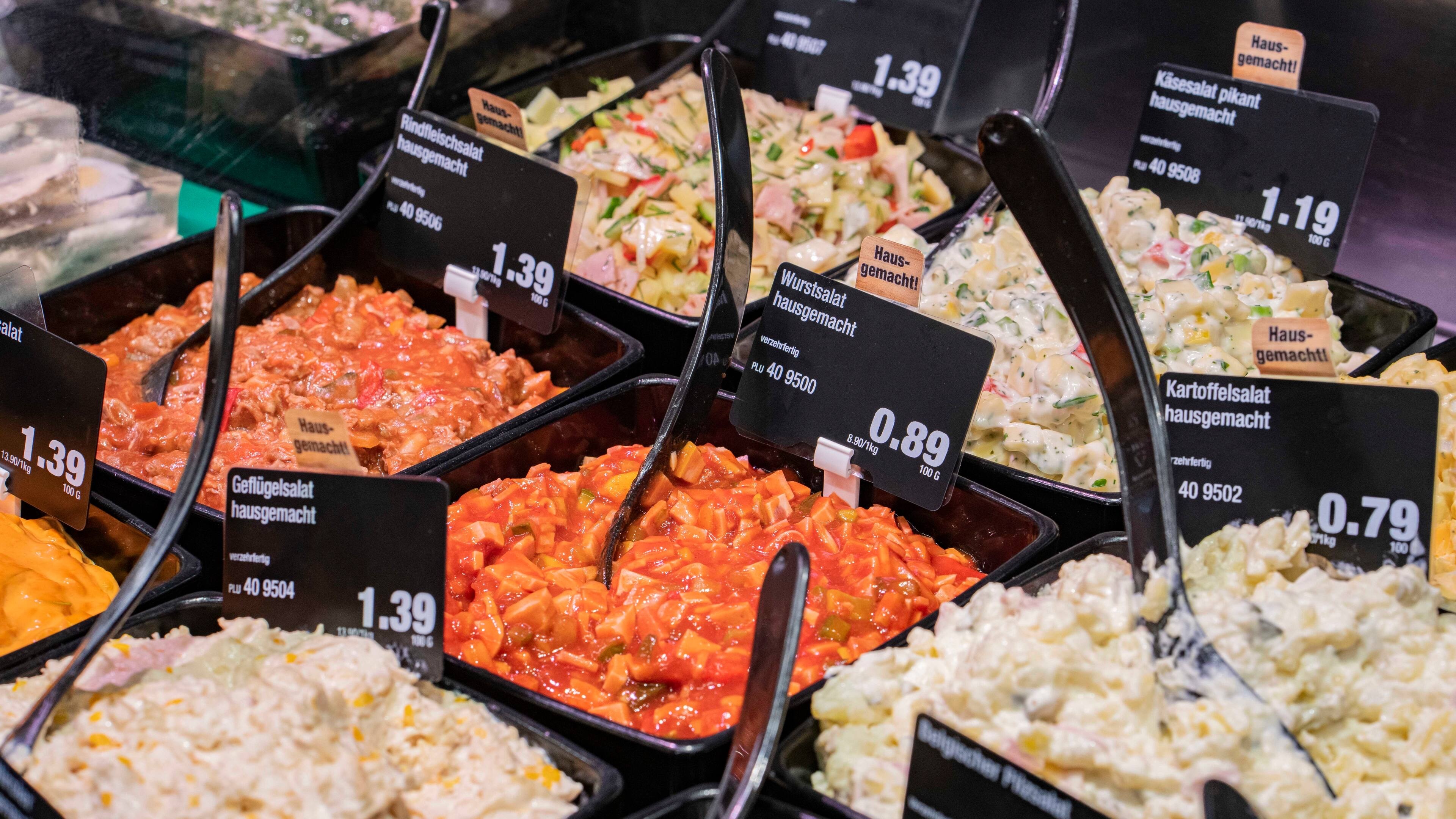 Mehrere Schüsseln voller verschiedener Salate in der Auslage einer Bedientheke.