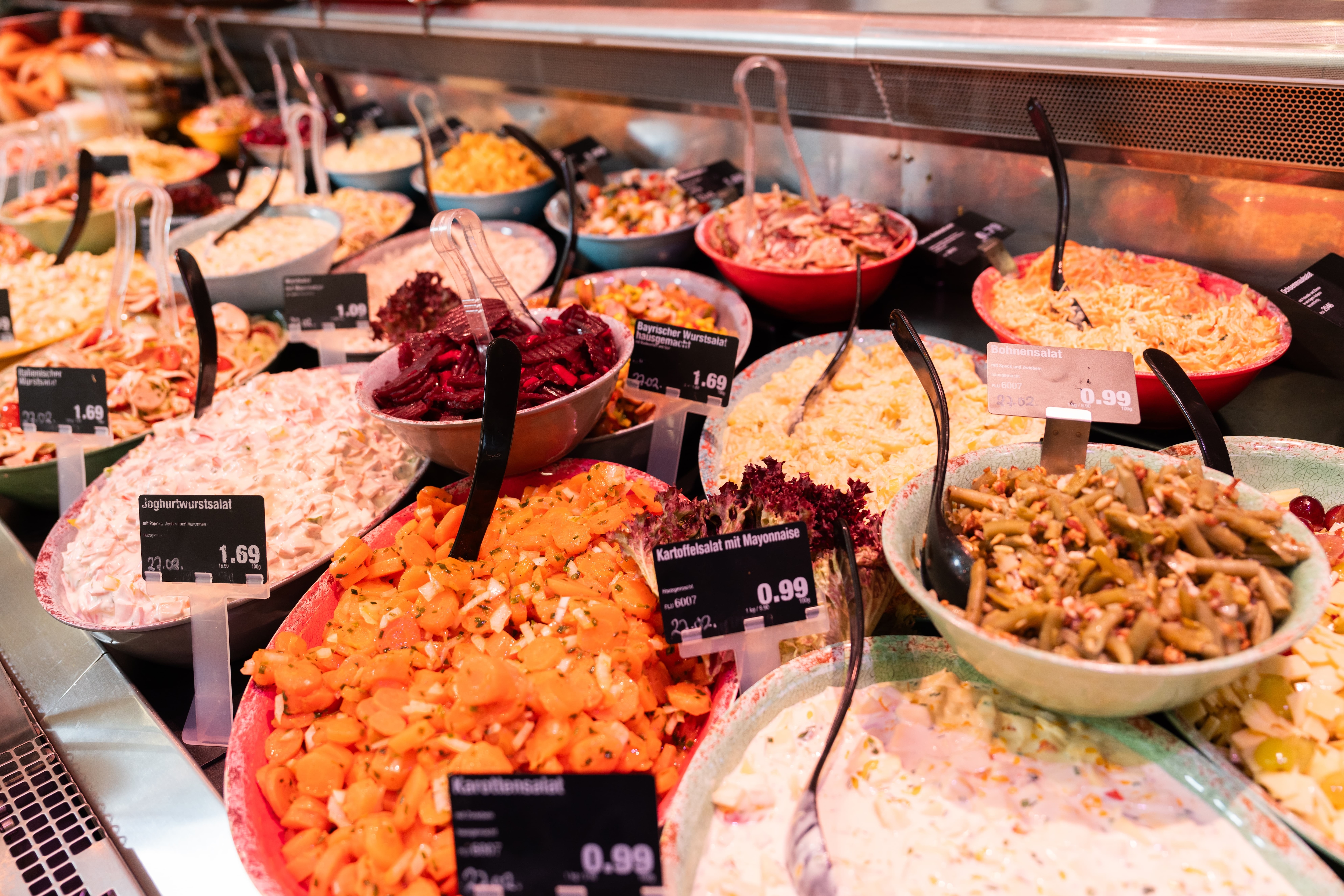 Schalen mit verschiedenen Salaten in der Auslage einer Frischetheke.
