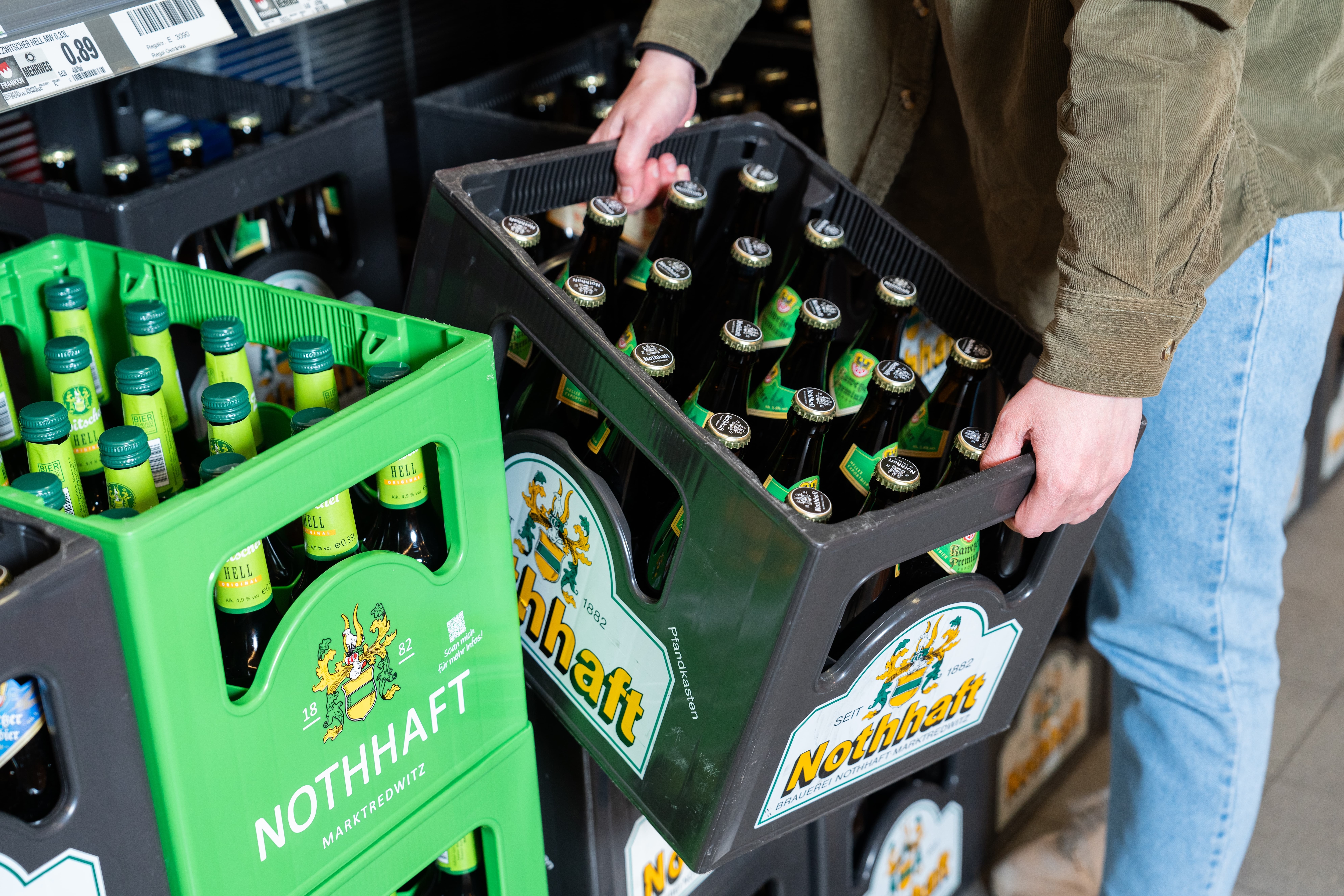 Eine Person hebt einen Kasten des regionalen Bieres von der Brauerei Nothhaft an.