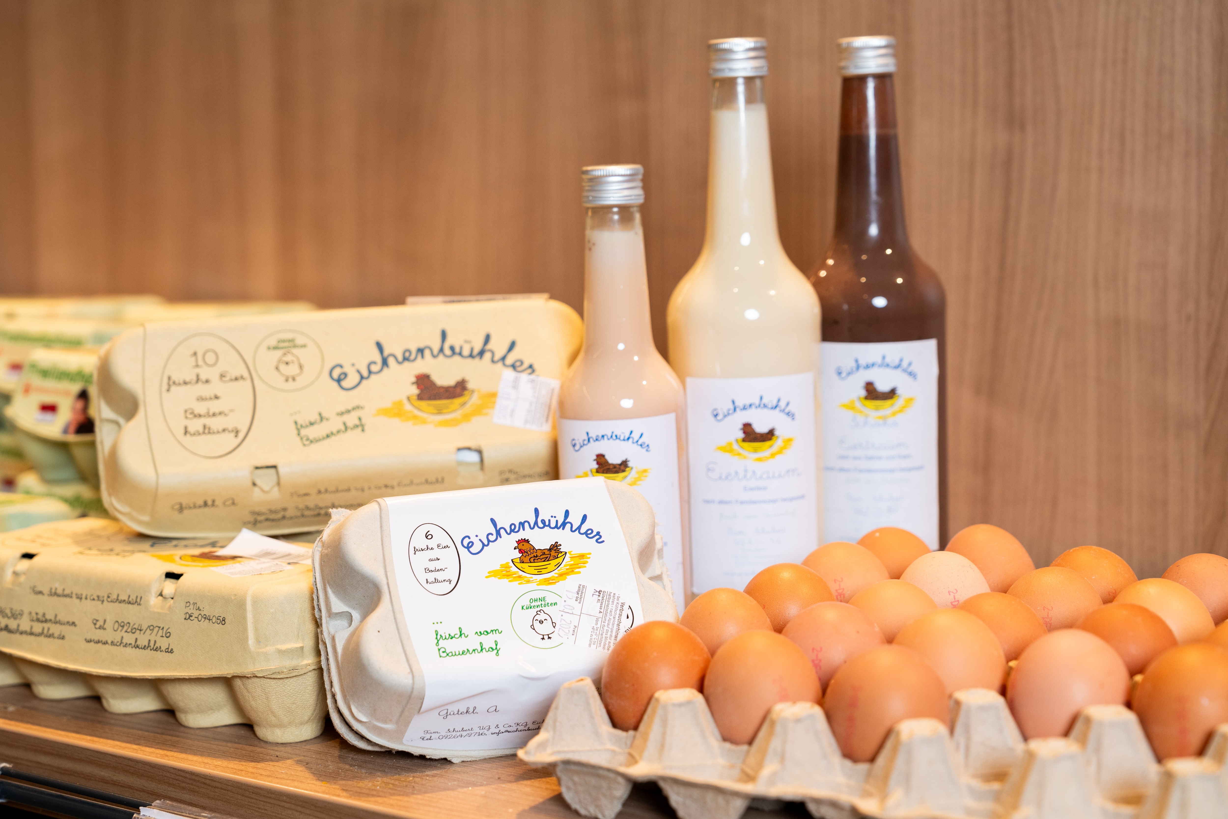 Verschiedene Produkte von Eichenbühler sind arrangiert auf einem Regalbrett: Eier, Eierkartons, Eierlikör.