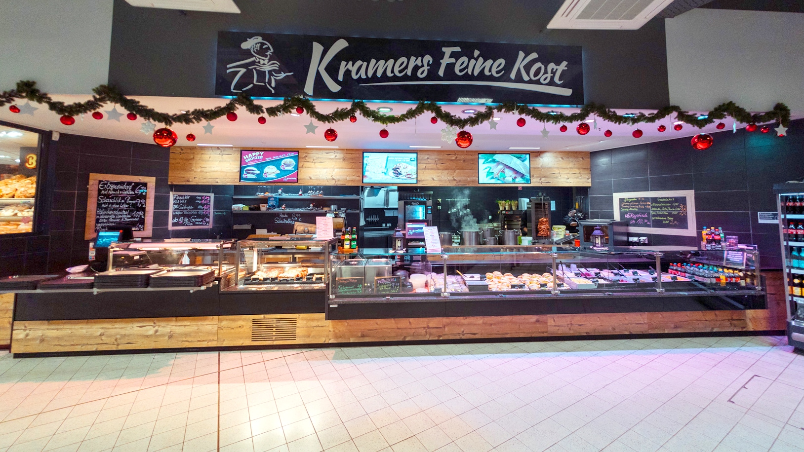 Eine heiße Theke über der ein Schild hängt auf dem steht: "Kramers Feine Kost"
