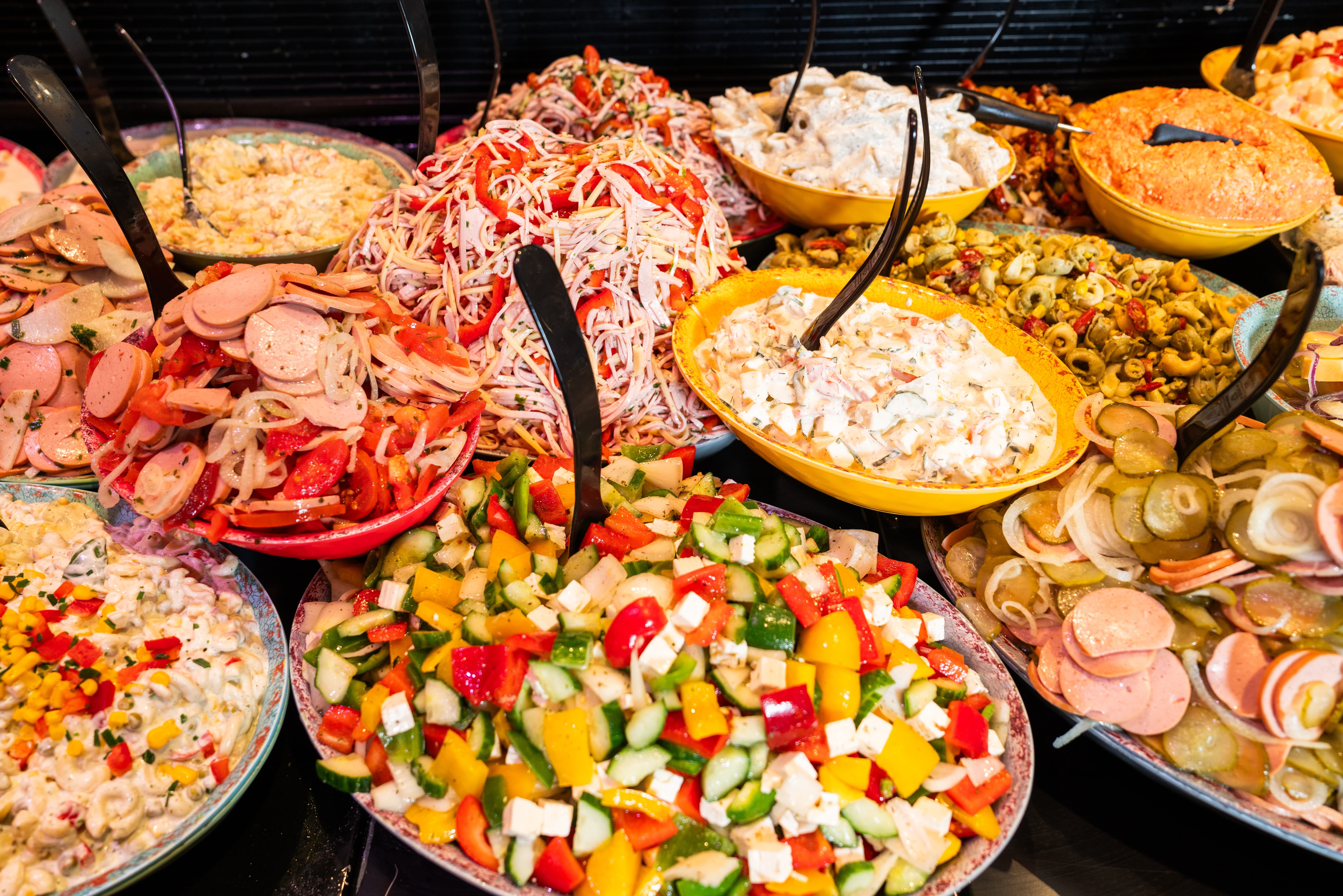 Schalen mit verschiedenen Salaten in der Auslage einer Theke.