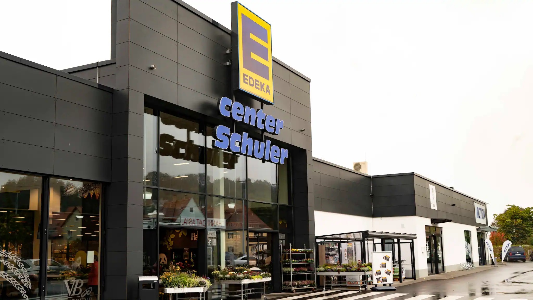 Haupteingang des EDEKA center Schuler vom verregneten Parkplatz aus gesehen.