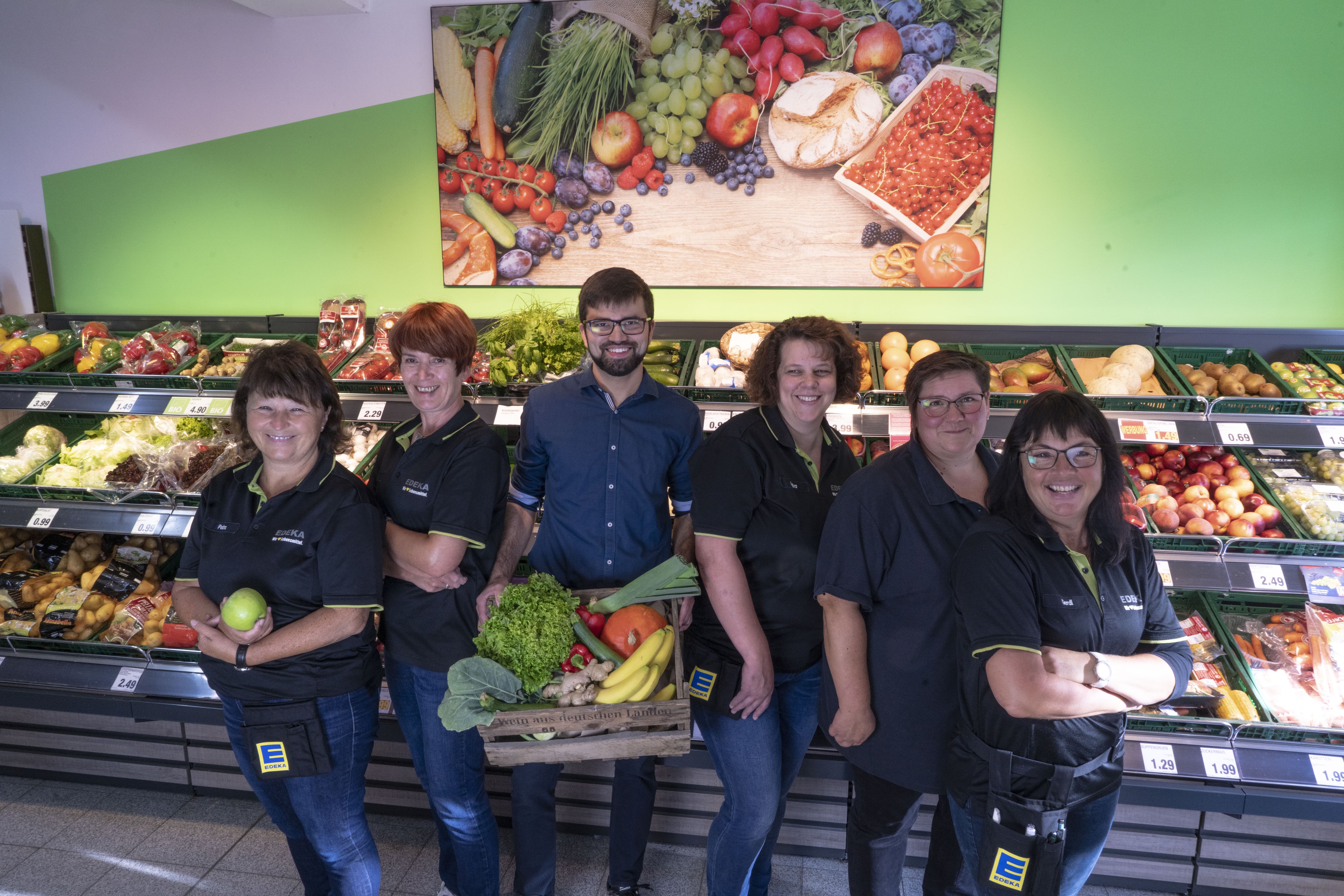 Gruppenfoto des Teams dieses EDEKA-Markts, aufgenommen in der Obst- und Gemüseabteilung.