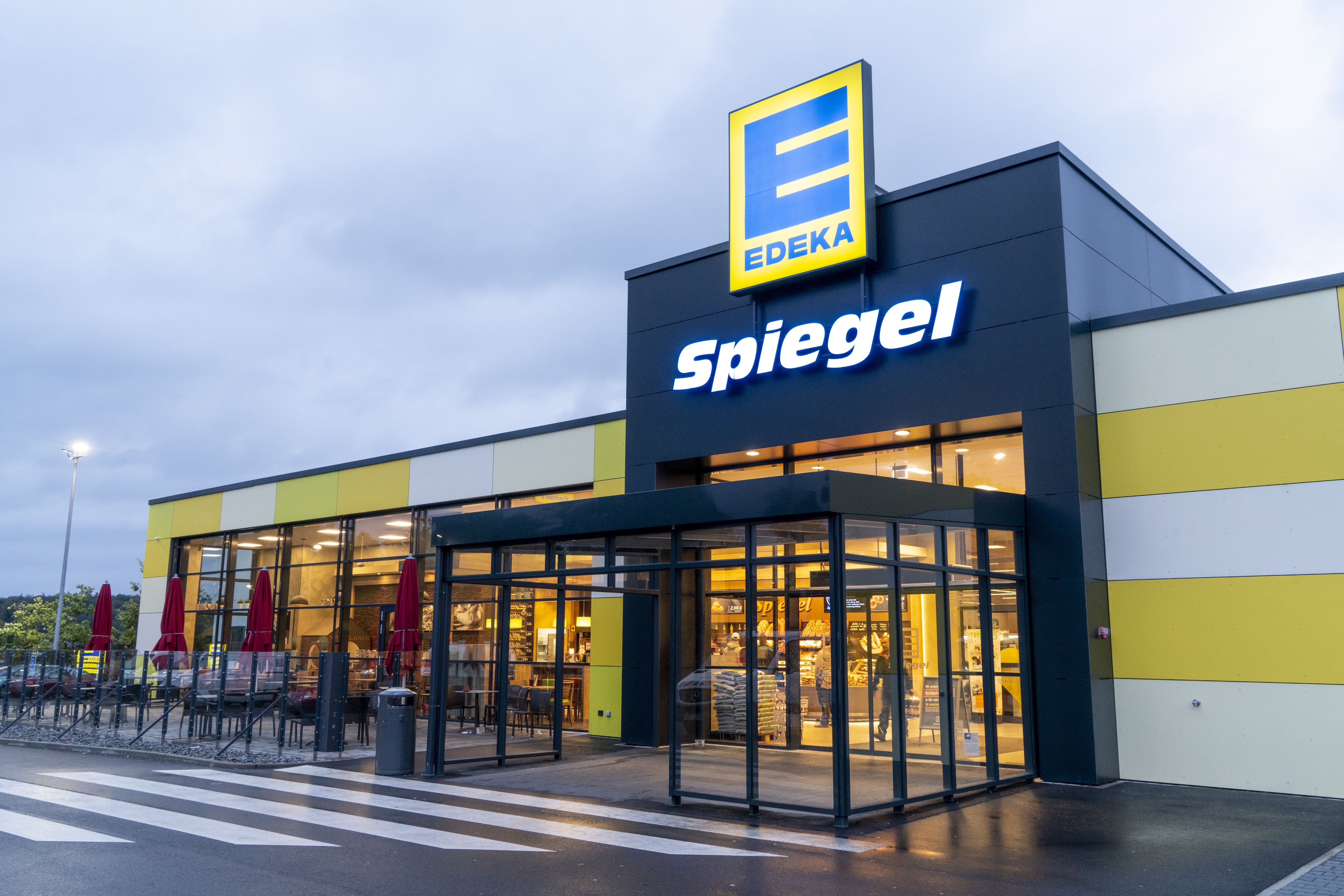 Front des Markts, bei regnerischem Wetter, mit dem Schriftzug EDEKA Spiegel über dem Eingang.
