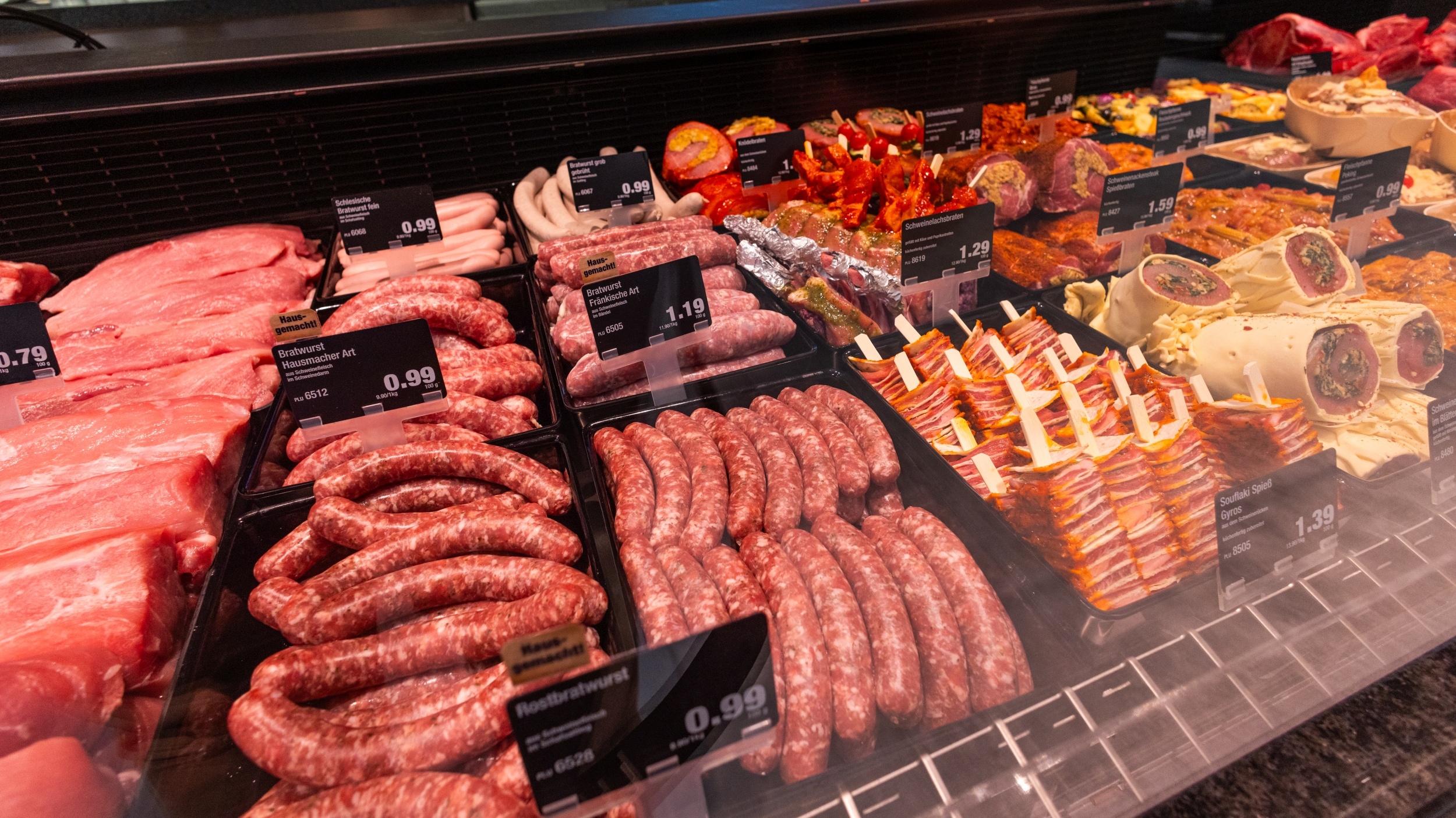 Schweinefilet, diverse Sorten Bratwurst, Souflaki Spieße, Schweinerollbraten und verschieden marinierte Fleischsorten angeboten im Bereich der Frische-Fleisch-Theke