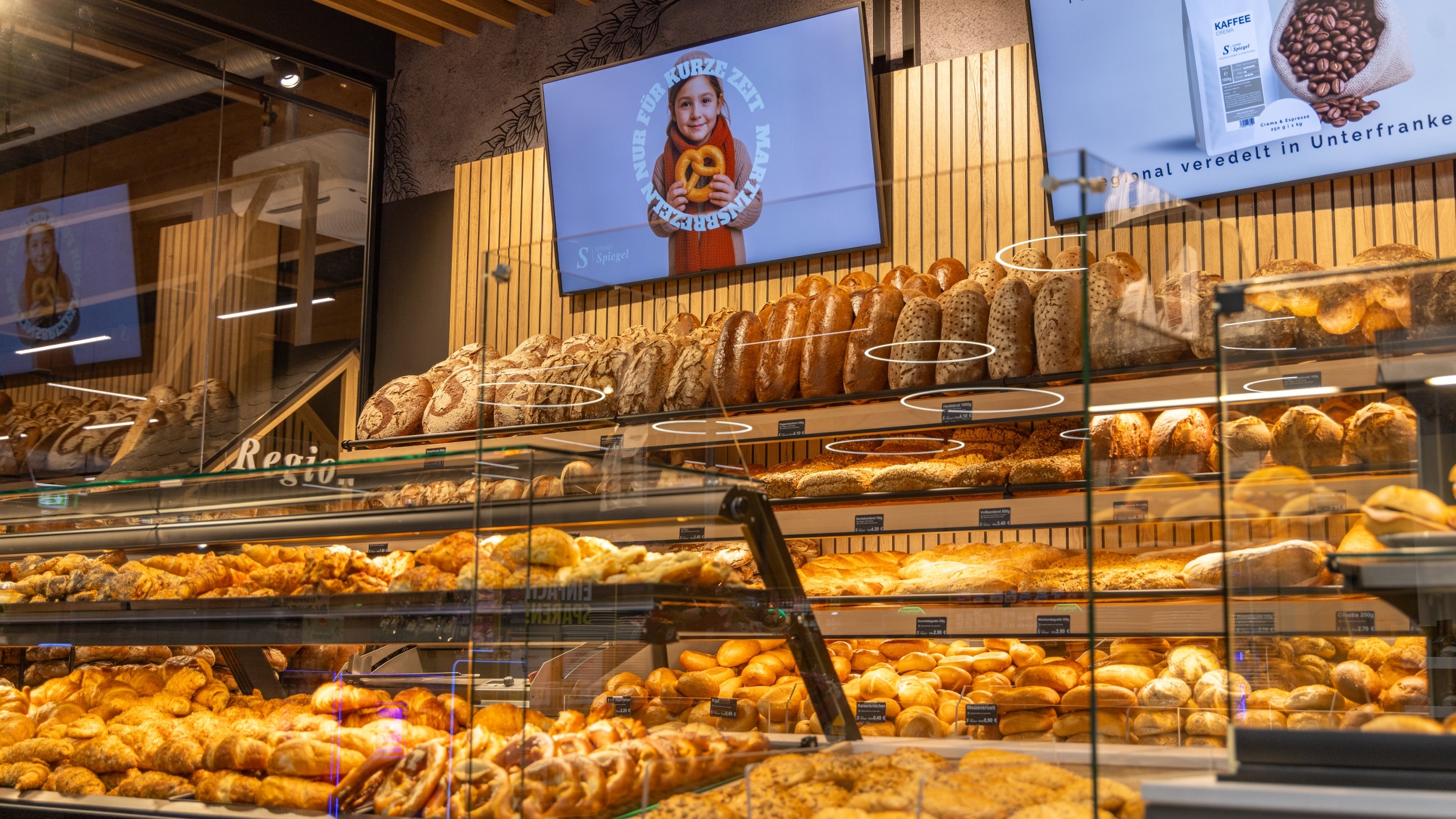 Teilansichter der Bäckerei mit Brotregalen, Brötchen-Boxen und Auslage für Brezeln und Croissants