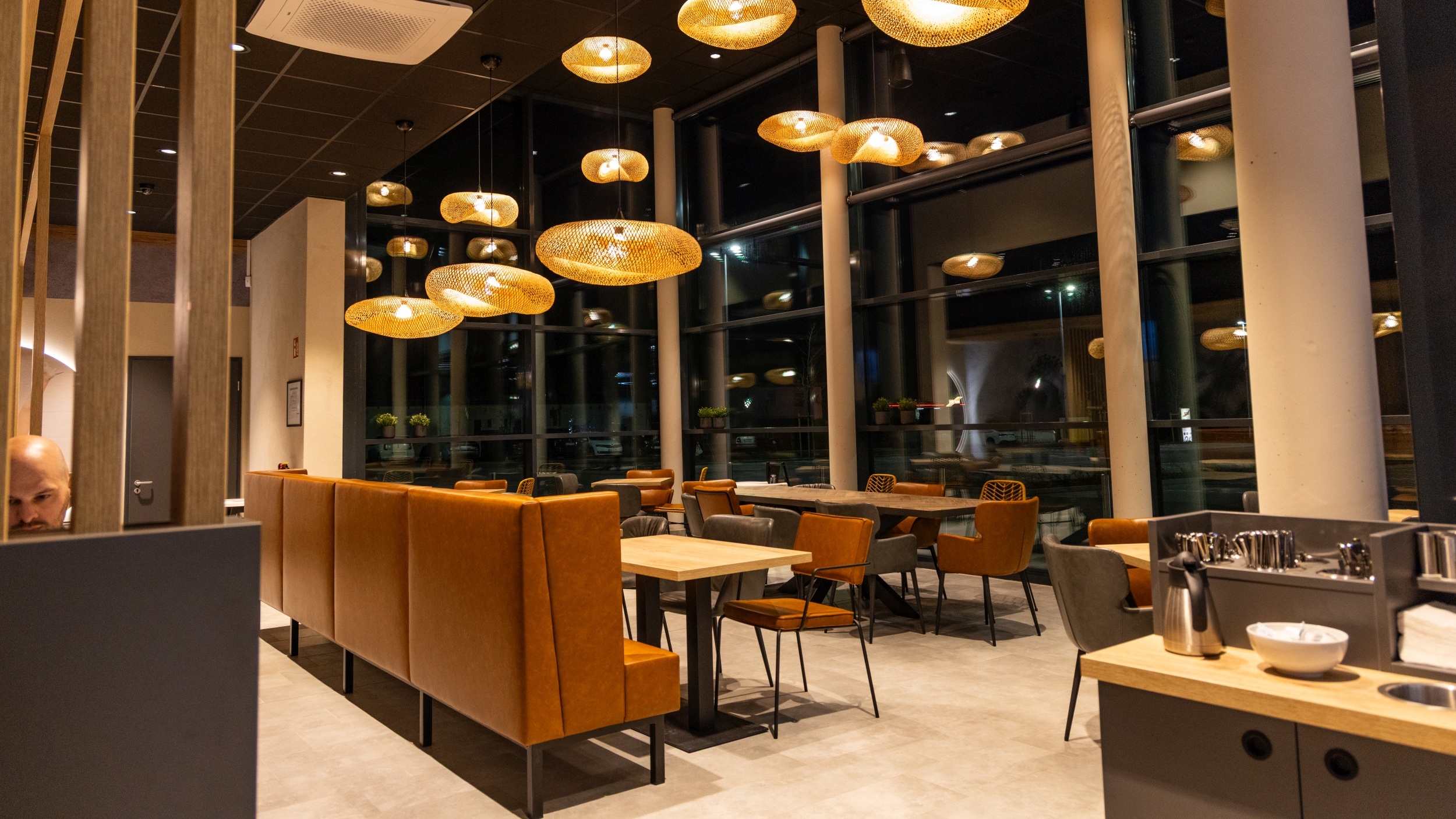 Restaurant, Ess- und Sitz-Bereich innerhalb des Marktes mit Tische, Stühlen und Sitzbänken und großer Glasfront