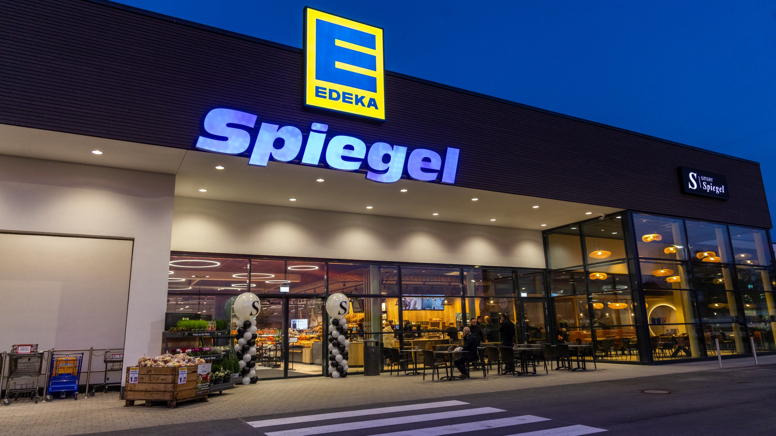 Außenansicht des Marktes Edeka Spiegel bei Nacht mit beleuchtetem Logo an der Fassade.