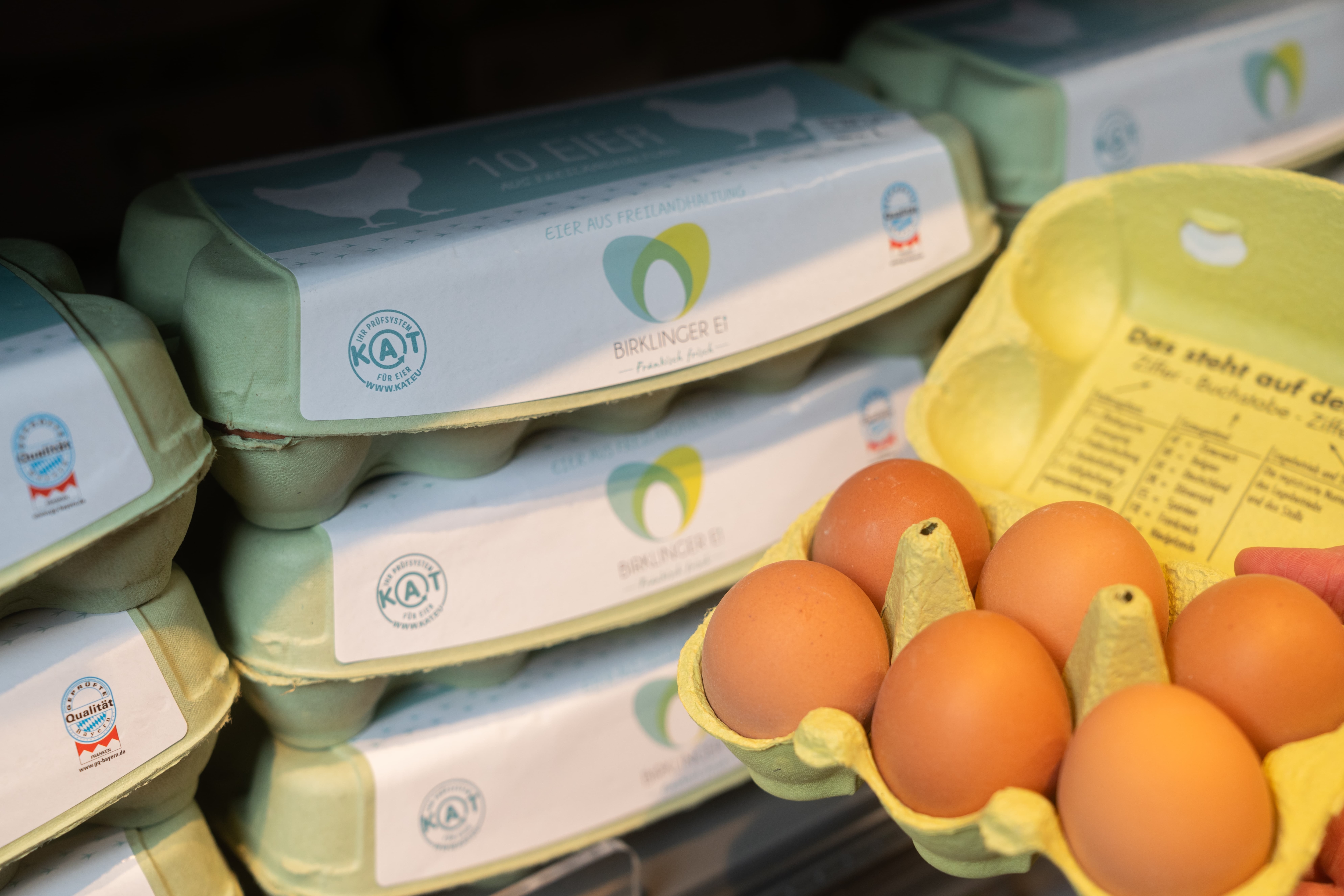 Ein Regal mit grünen Eierkartons. Einer von ihnen ist geöffnet.