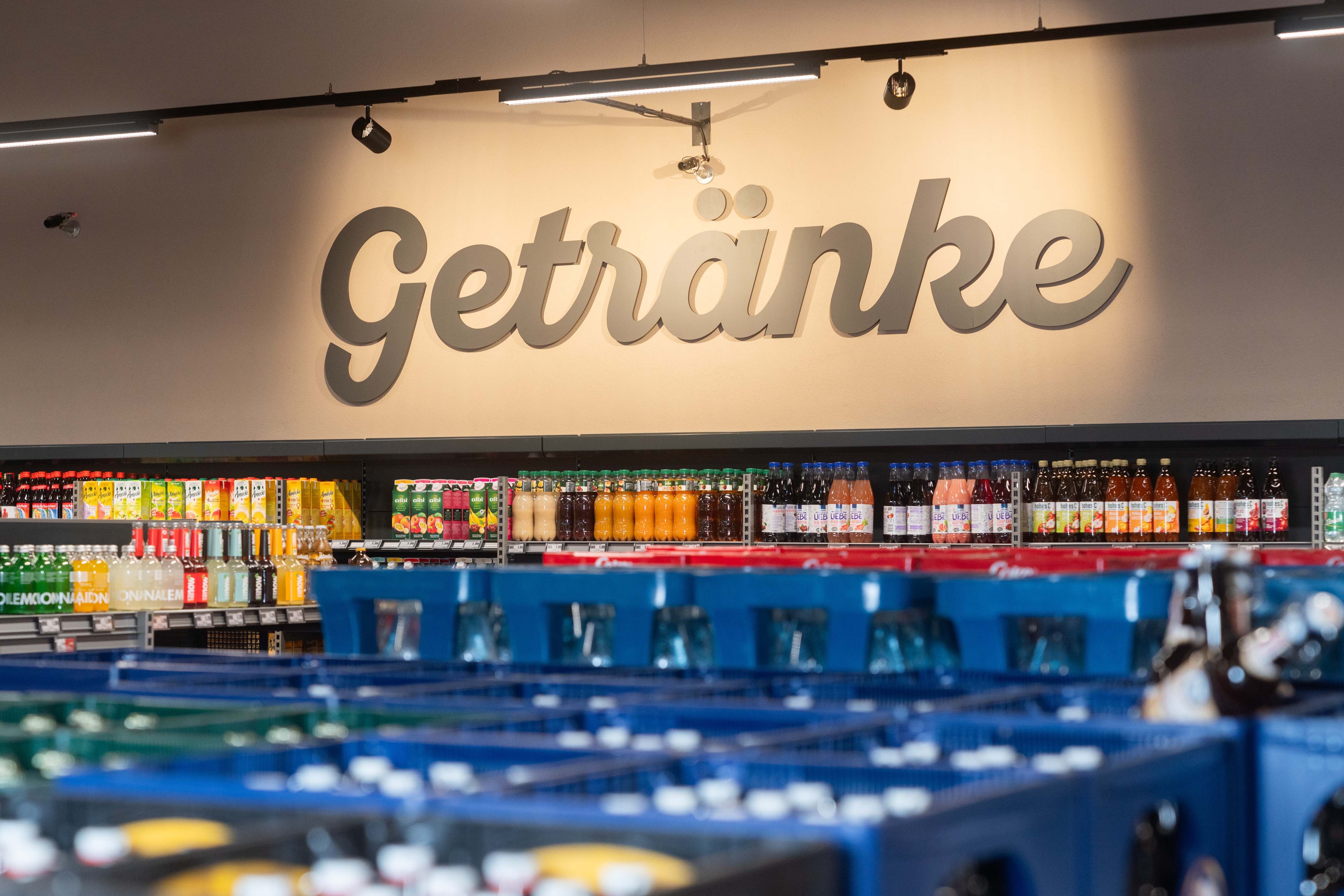 Über einem Kühlregal mit Flaschen steht der Schriftzug: Getränke.