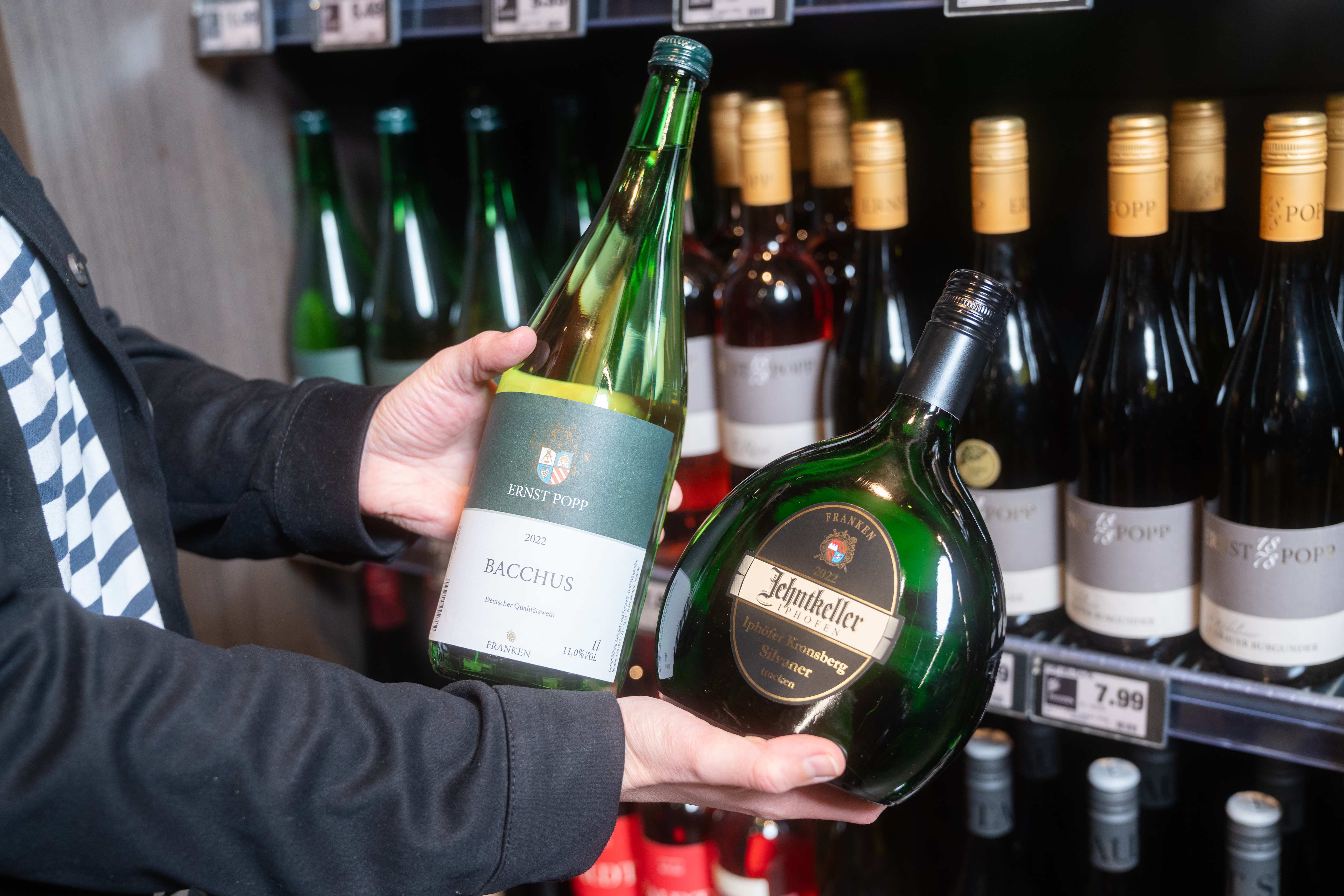 Zwei Hände halten zwei Weinflaschen. In der linken Bacchus von Ernst Popp und in der rechten Zehntkeller Silvaner