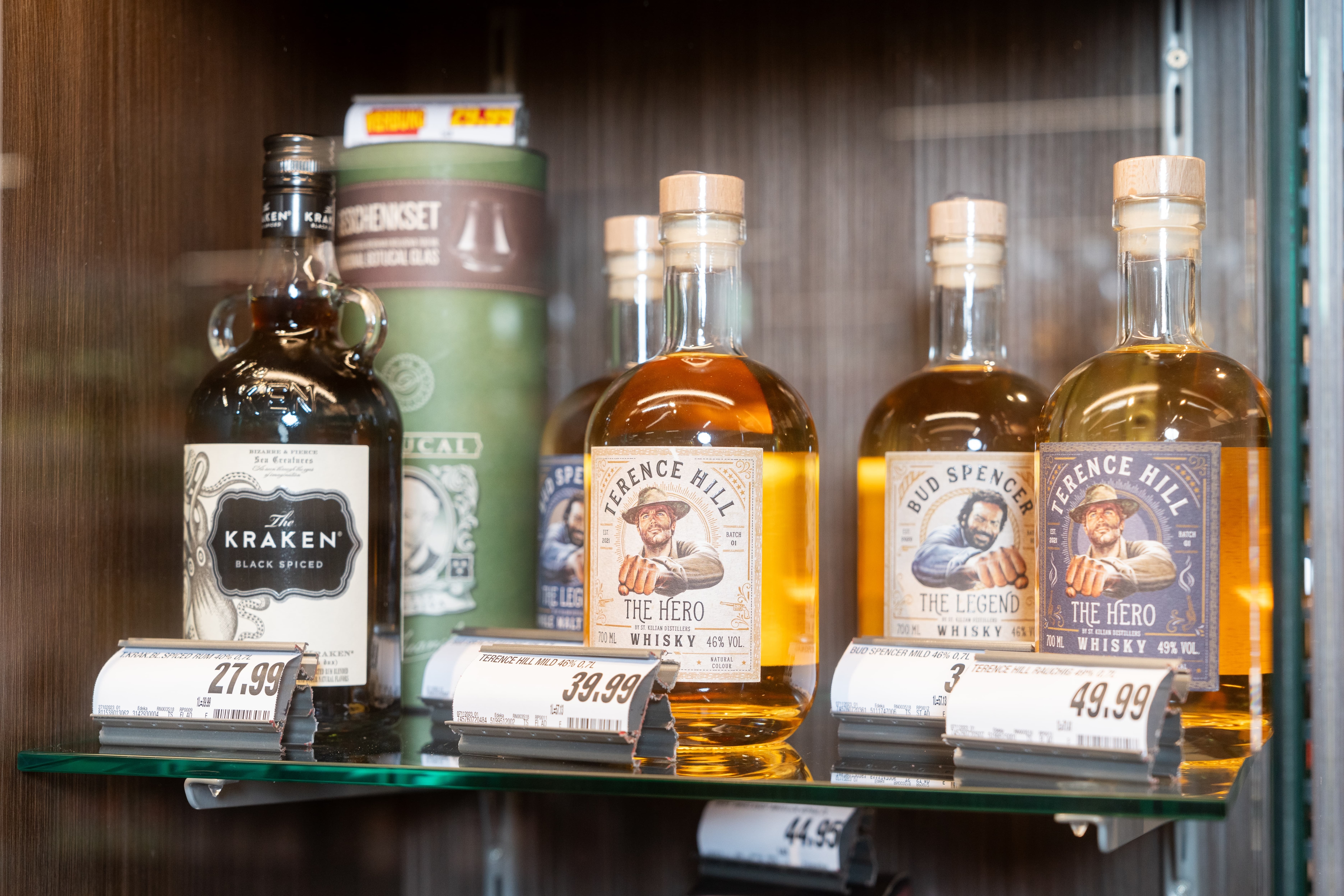 In einer Vitrine stehen eine Flasche Kraken Rum und vier Flaschen Whisky mit Terence Hill und Bud Spencer.